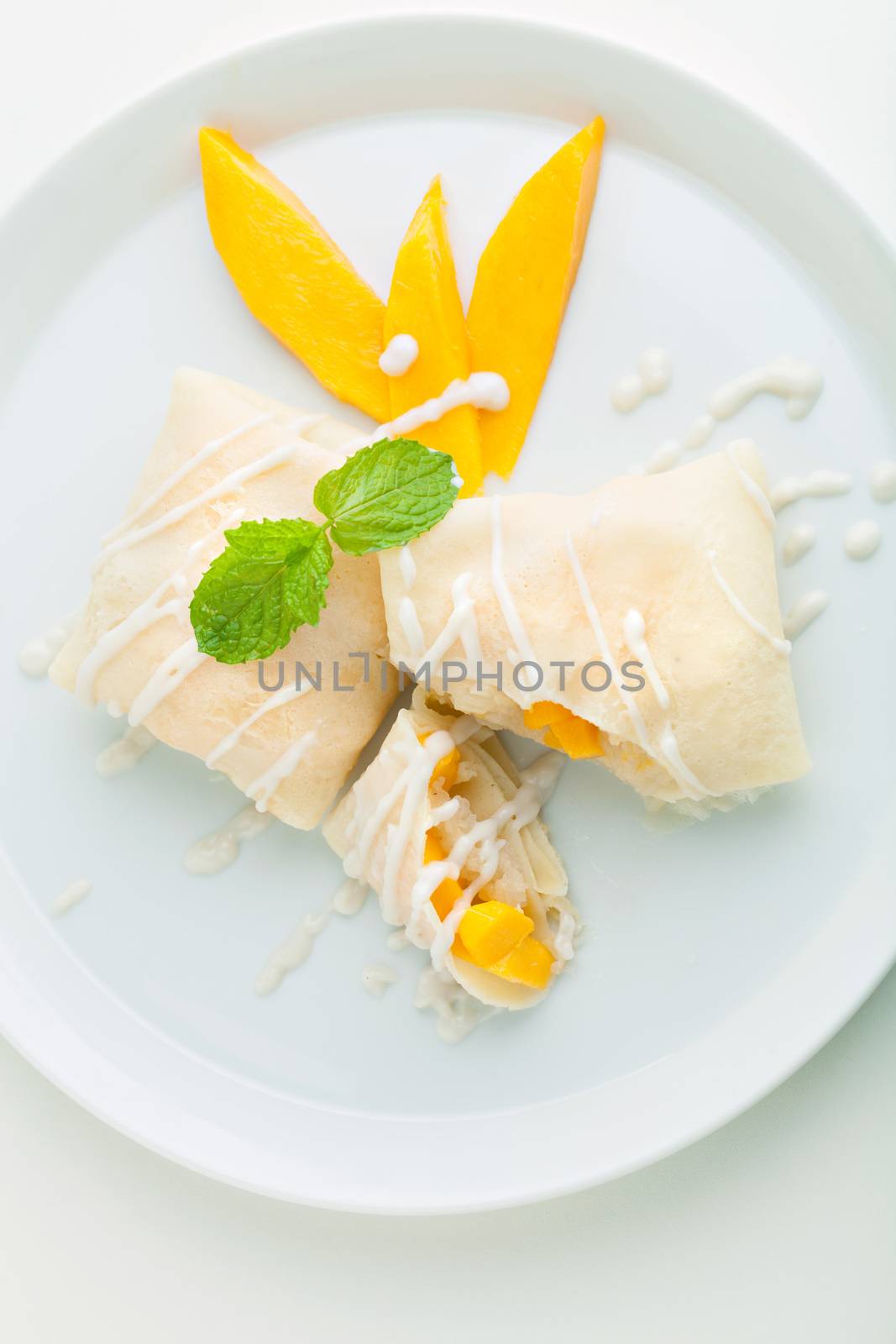 Thai style tropical dessert crepes filled with fresh mango and sticky rice. Top down overhead view.