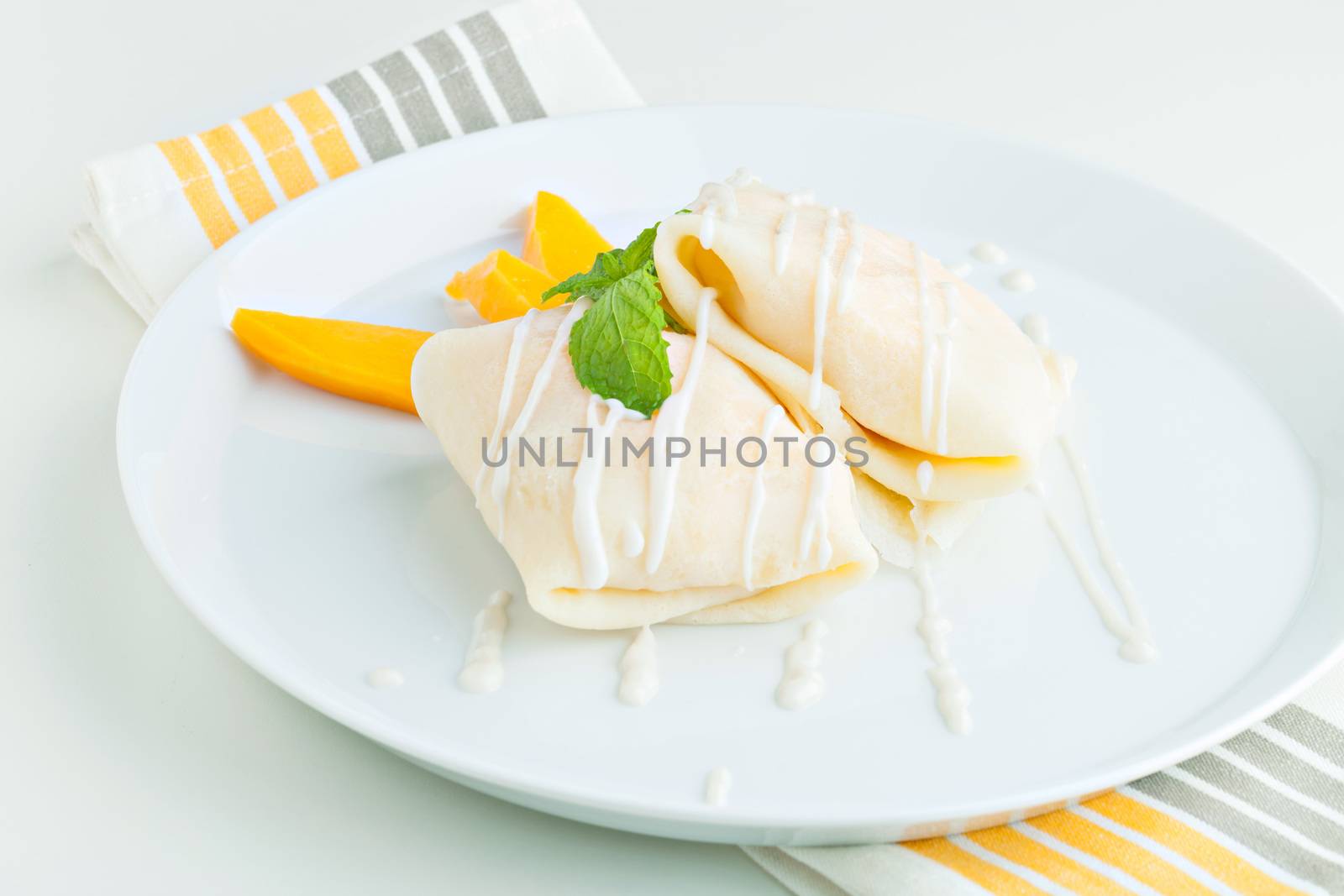 Thai style tropical dessert crepes filled with fresh mango and sticky rice. Shallow depth of field.