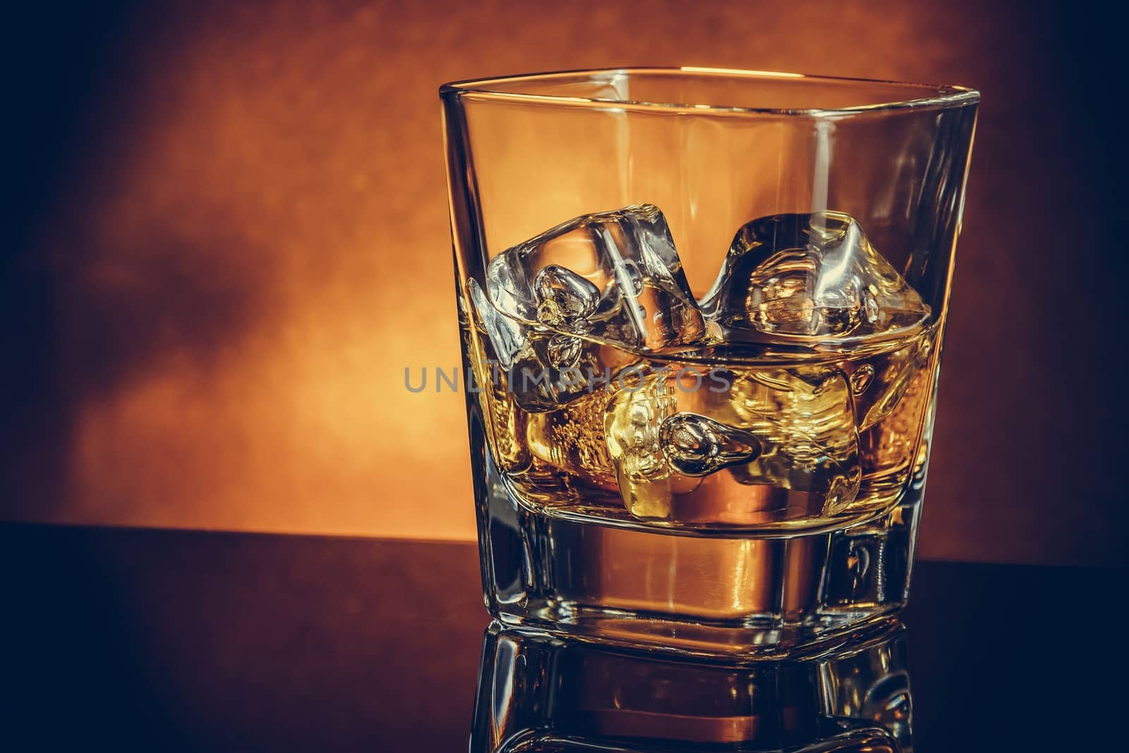 glass of whiskey on black table with reflection and gold background, warm atmosphere, time of relax with whisky with space for text