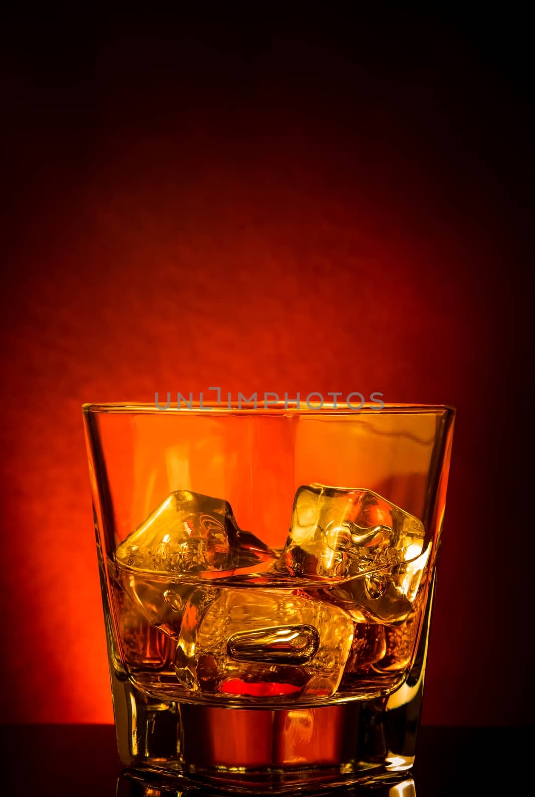 glass of whiskey on black table with reflection, red tint atmosphere, time of relax with whisky