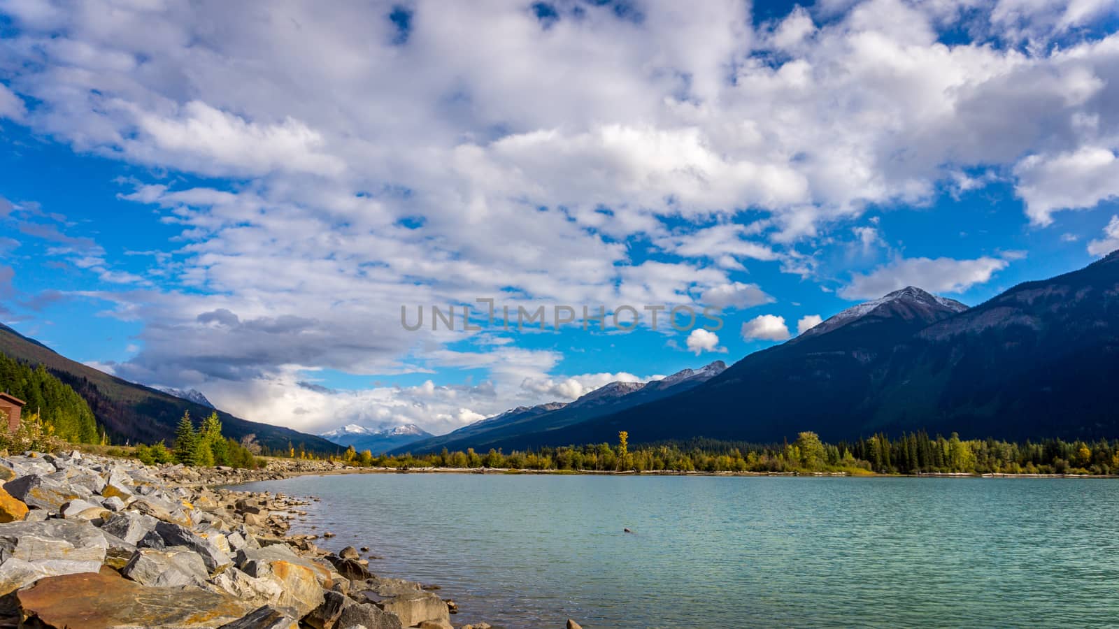 Moose Lake in Mount Robson Provincial Park in British Columbia, Canada under blue and partly cloudy sky. The mountains in the background are part of the Rocky Mountains