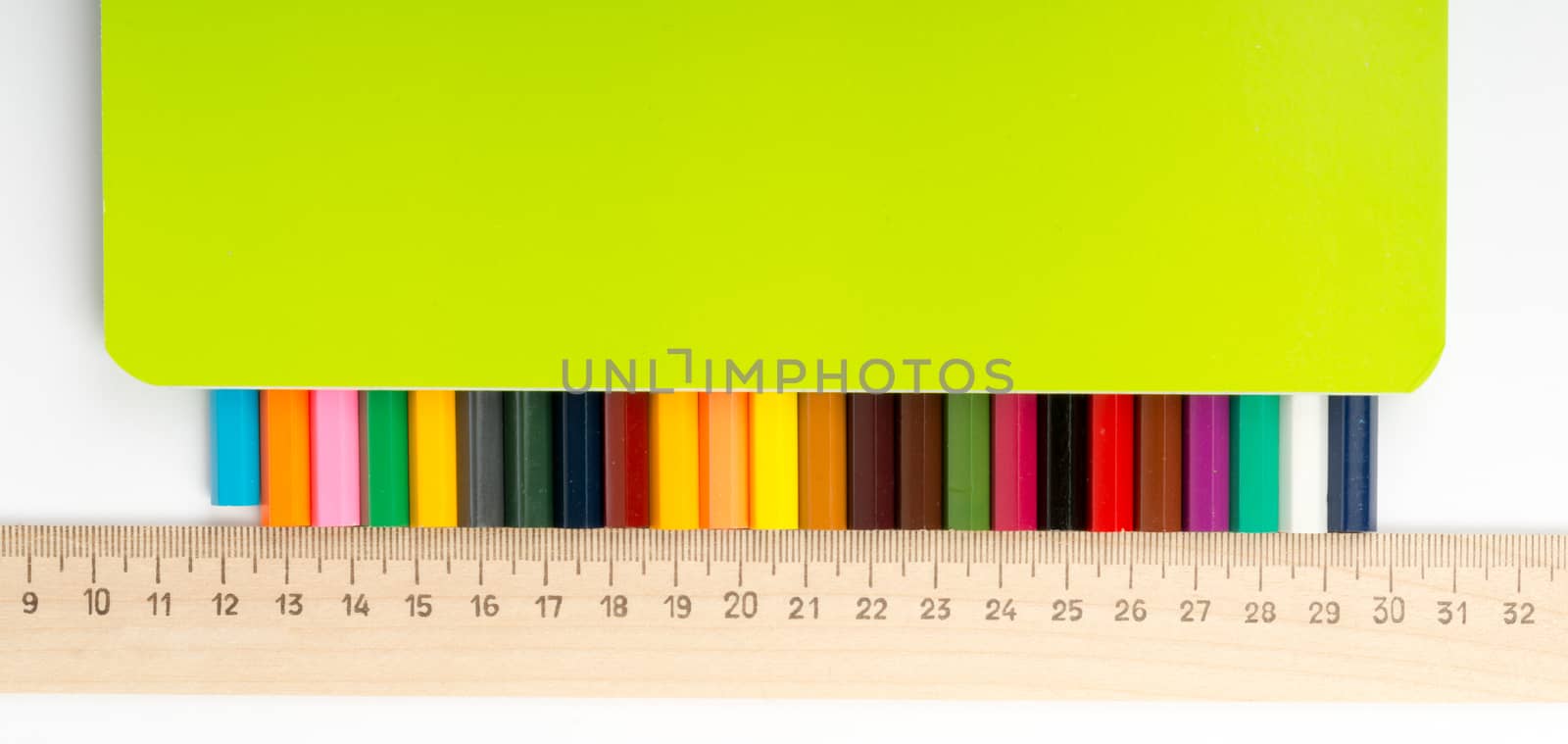 Set of crayons with ruler and copybook on isolated white background