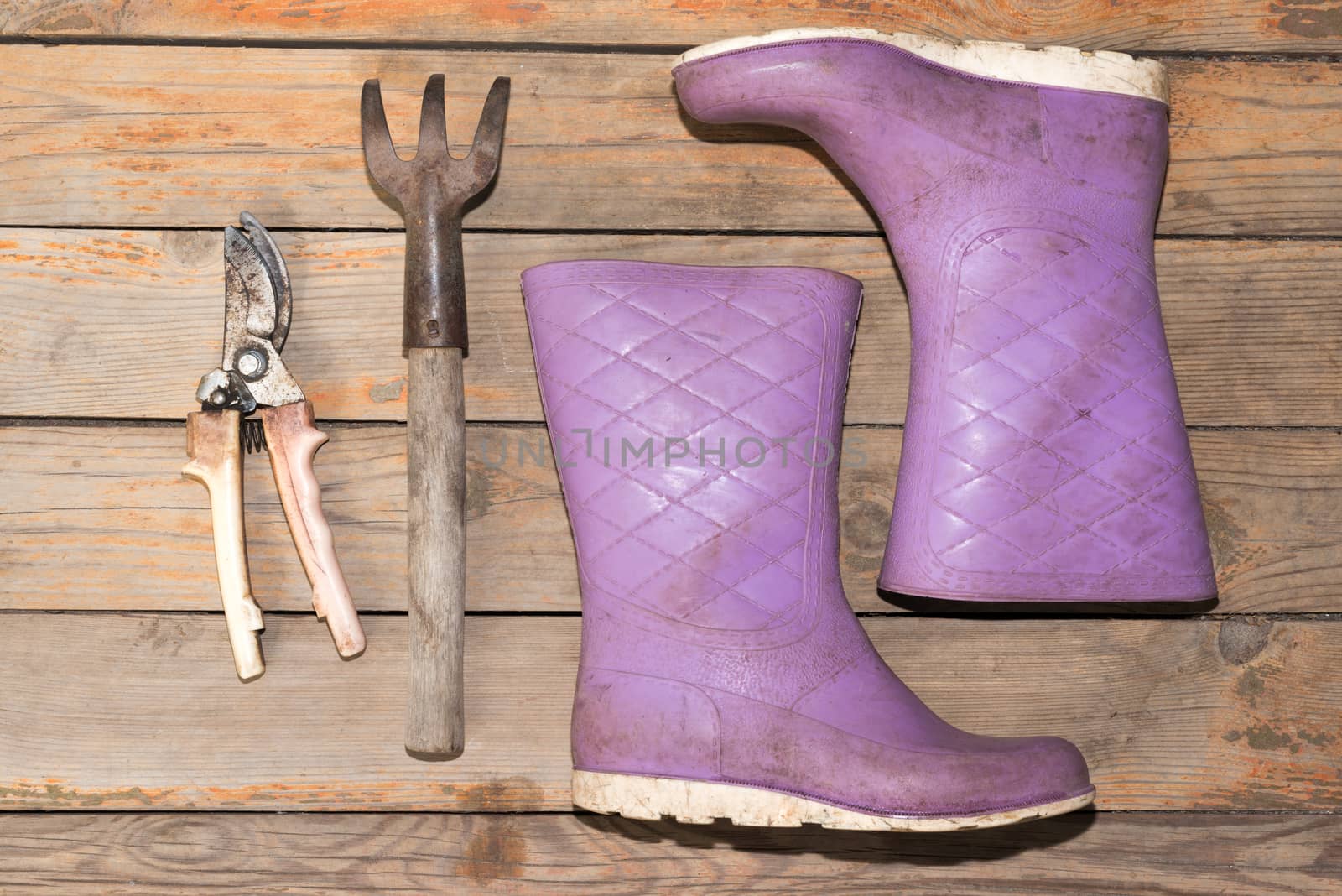 Old wooden texture background with tools and wellingtons, close up view