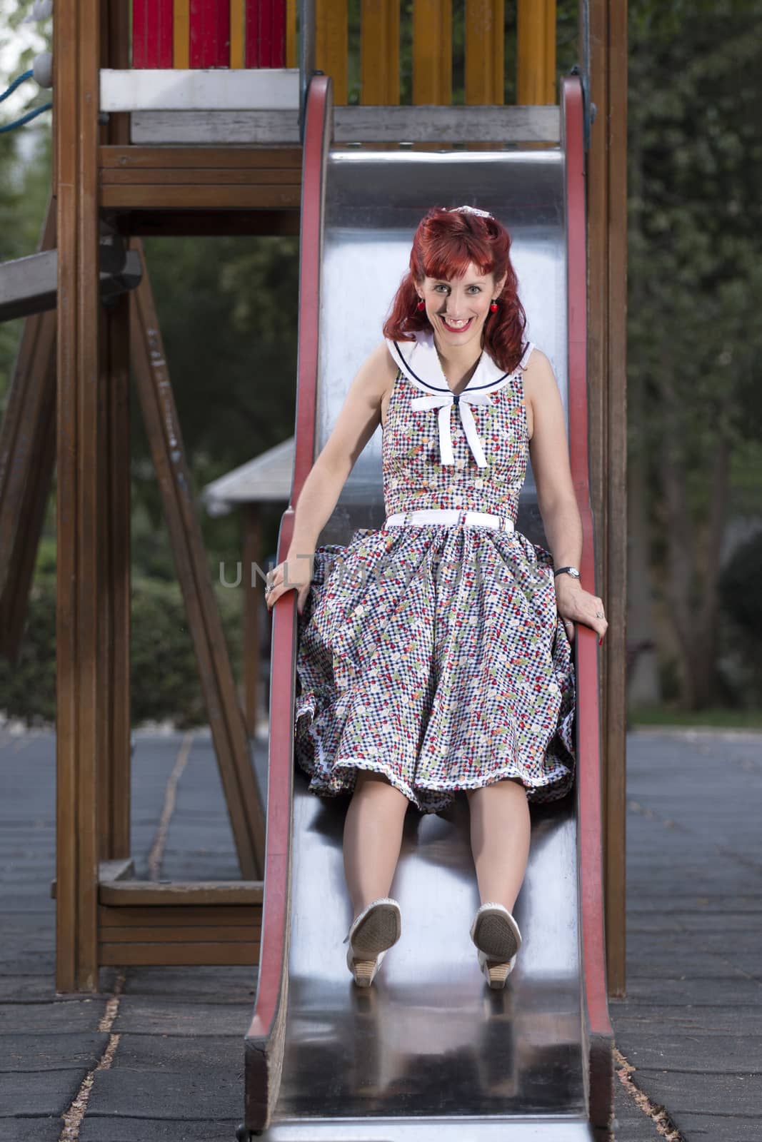 View of pinup young woman in vintage style clothing on a playground.