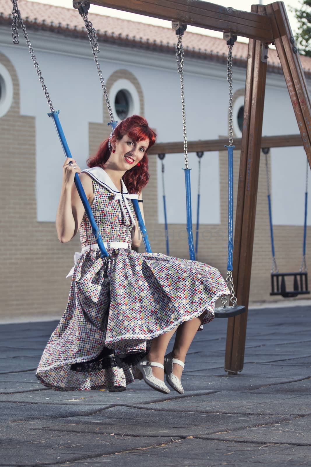 View of pinup young woman in vintage style clothing on a playground.