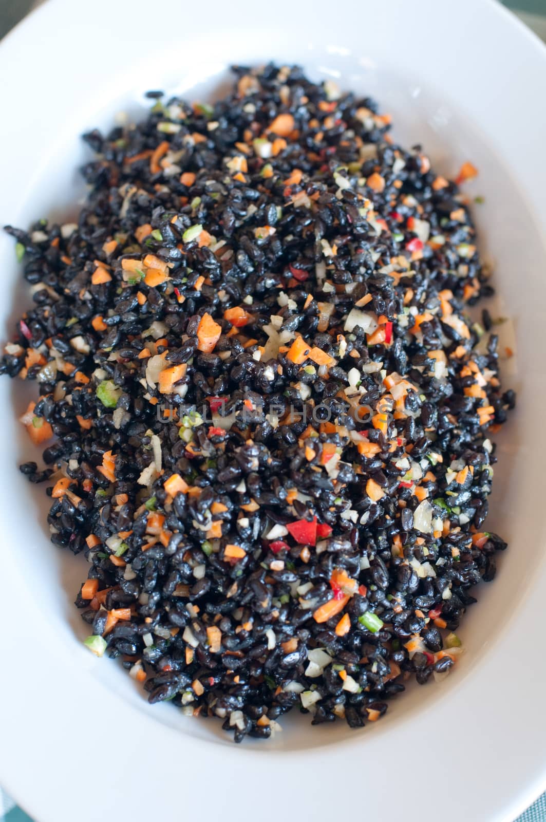 Black rice dish seasoned with tomatoes , carrots , olive oil and parsley