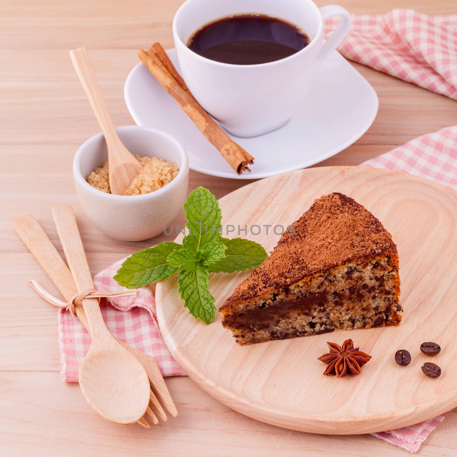 Homemade dark chocolate cake with cup of coffee on wooden background.
