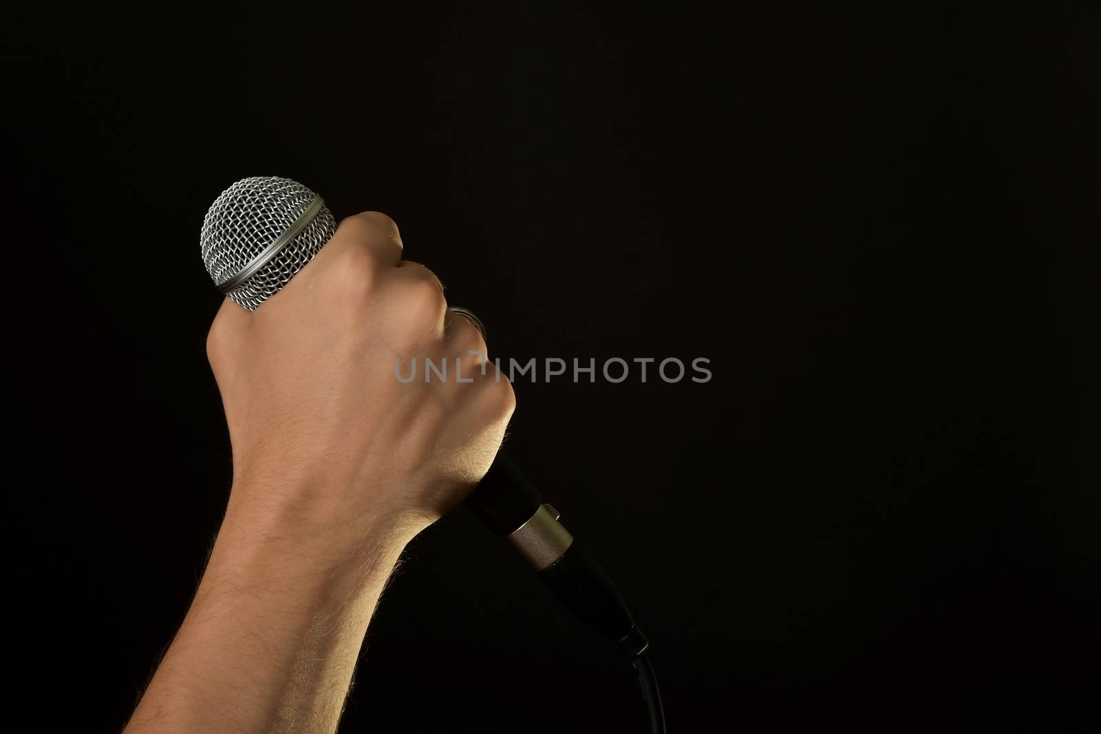 Male hand with microphone isolated on black by BreakingTheWalls