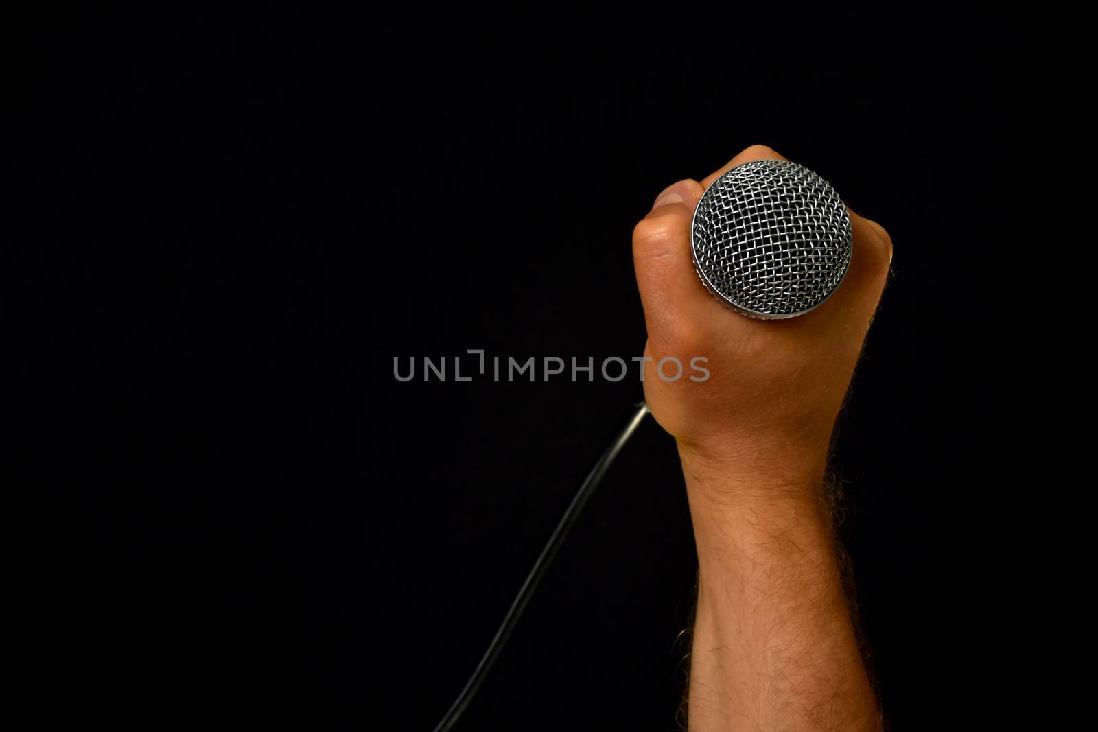 Male hand with microphone isolated on black by BreakingTheWalls