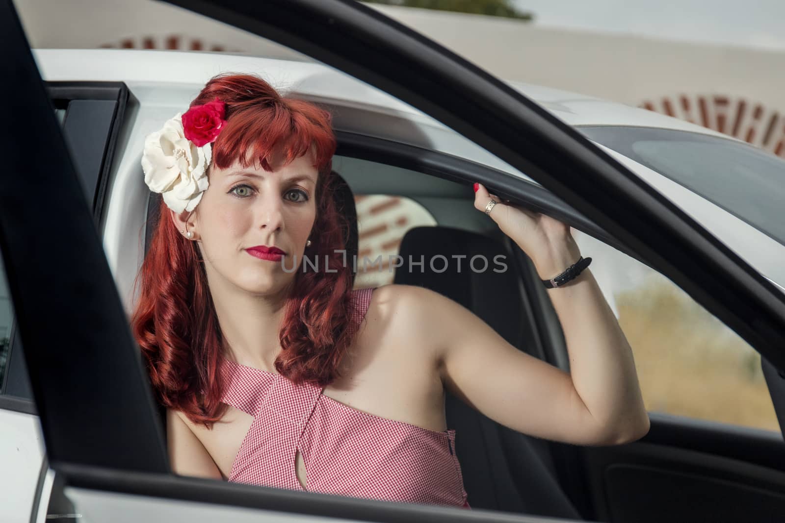 View of pinup young woman in vintage style clothing next to a white car.