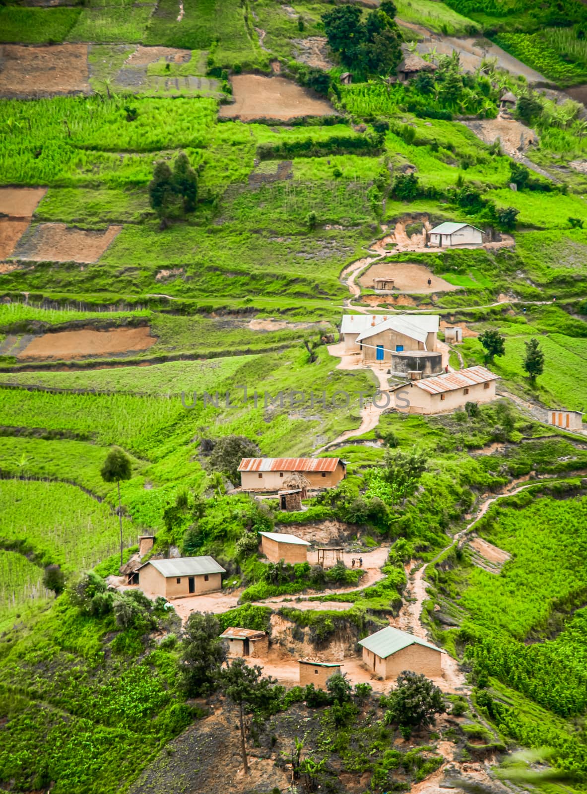 A view from high up of some houses and green agricultural land, set against slope in the rural area of the Kabale district in Southern Uganda.