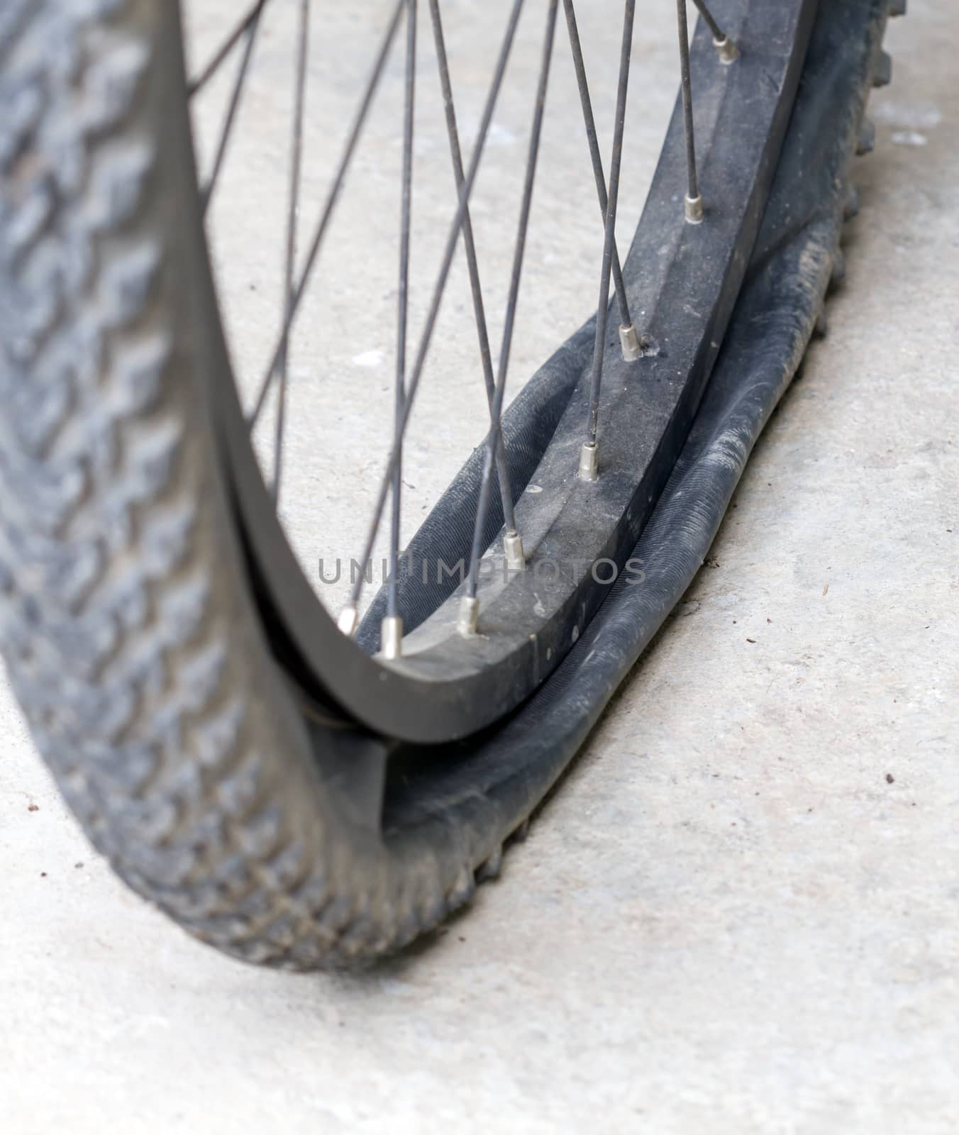 old Bicycle wheel with flat tyre on the concrete road