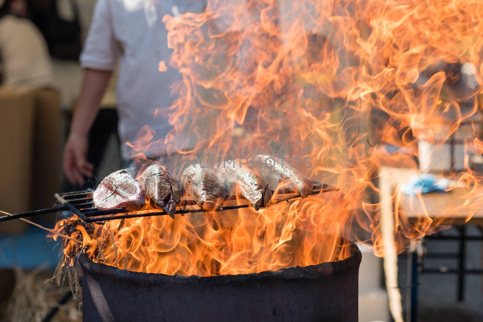 Japanese Bonito fish  being seared over an open flame in a barrel, kept raw on the inside.
