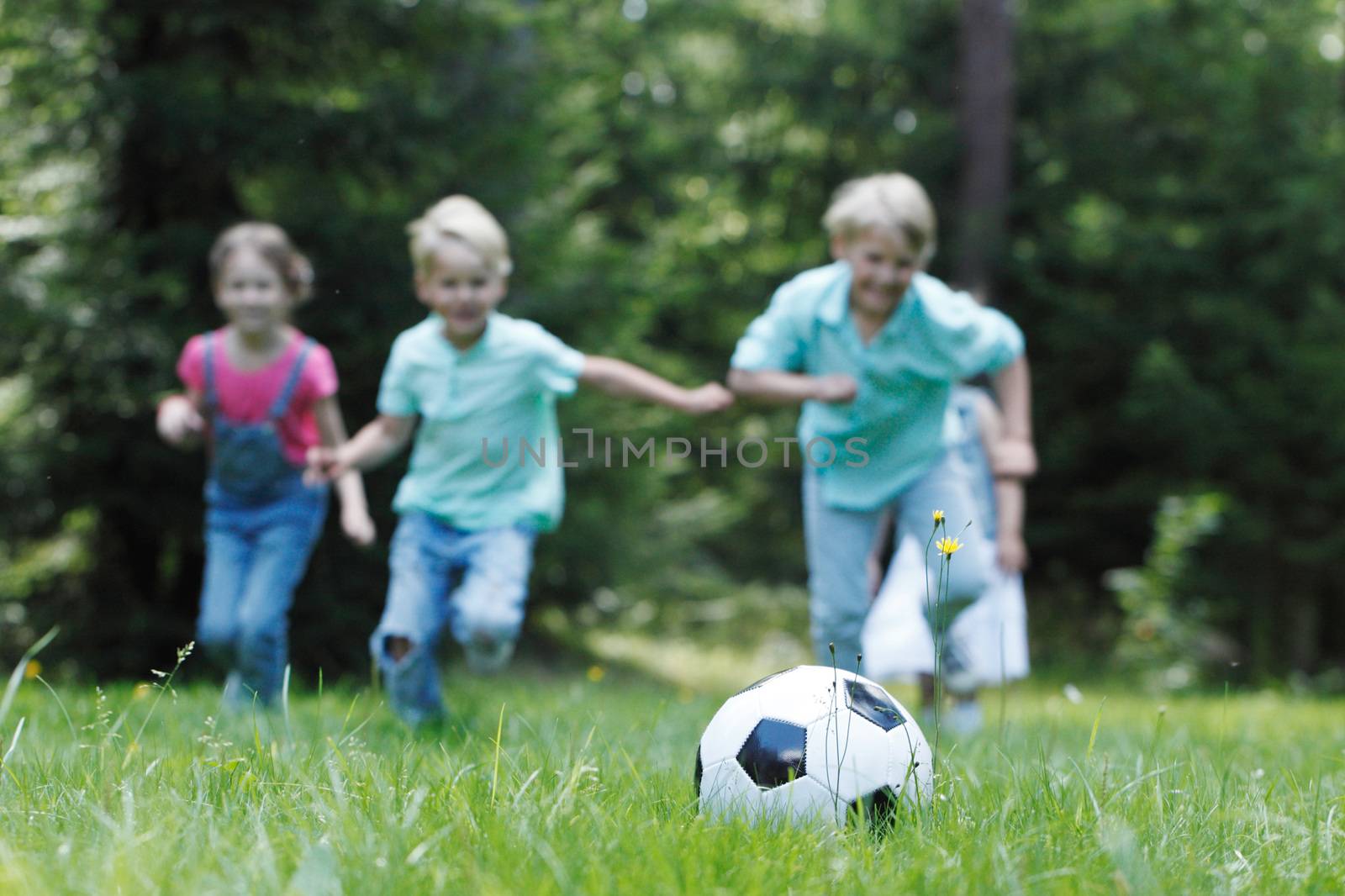 Happy children playing football in summer park