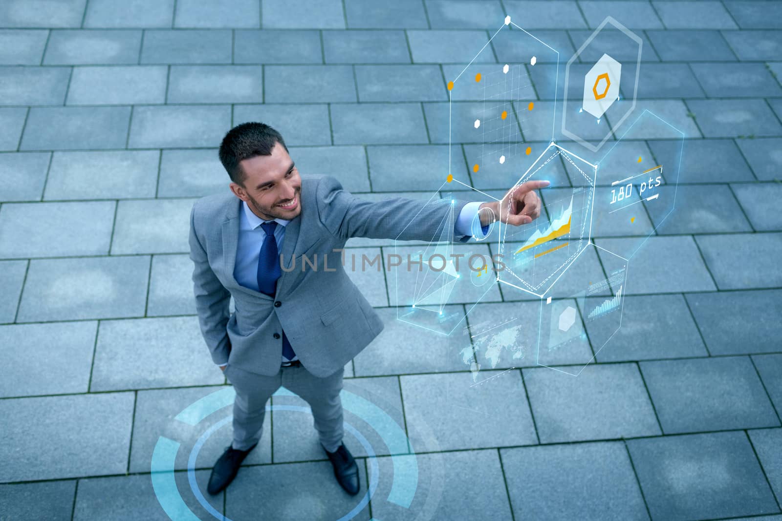 business, development, technology and people and concept - young smiling businessman pointing finger to virtual screens with graphs outdoors from top
