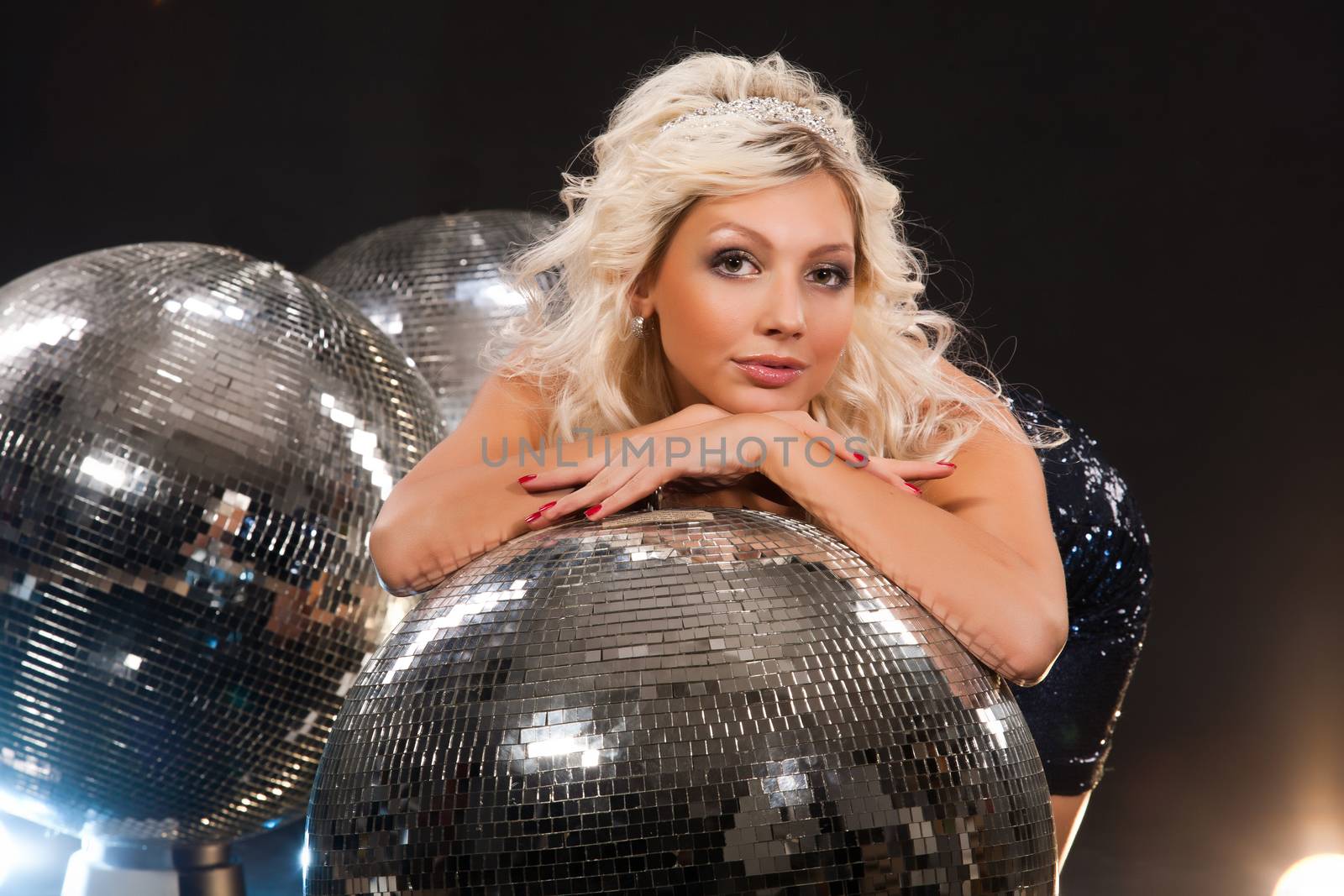 Young beautiful woman and mirror disco ball on a studio background