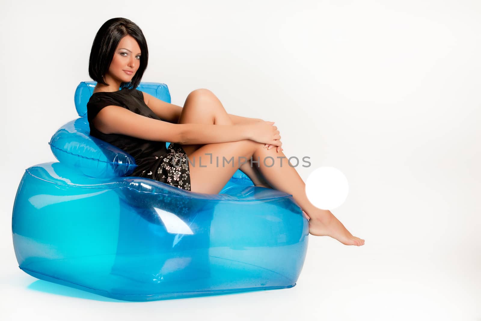 Young beautiful woman sitting on a blue inflatable armchair
