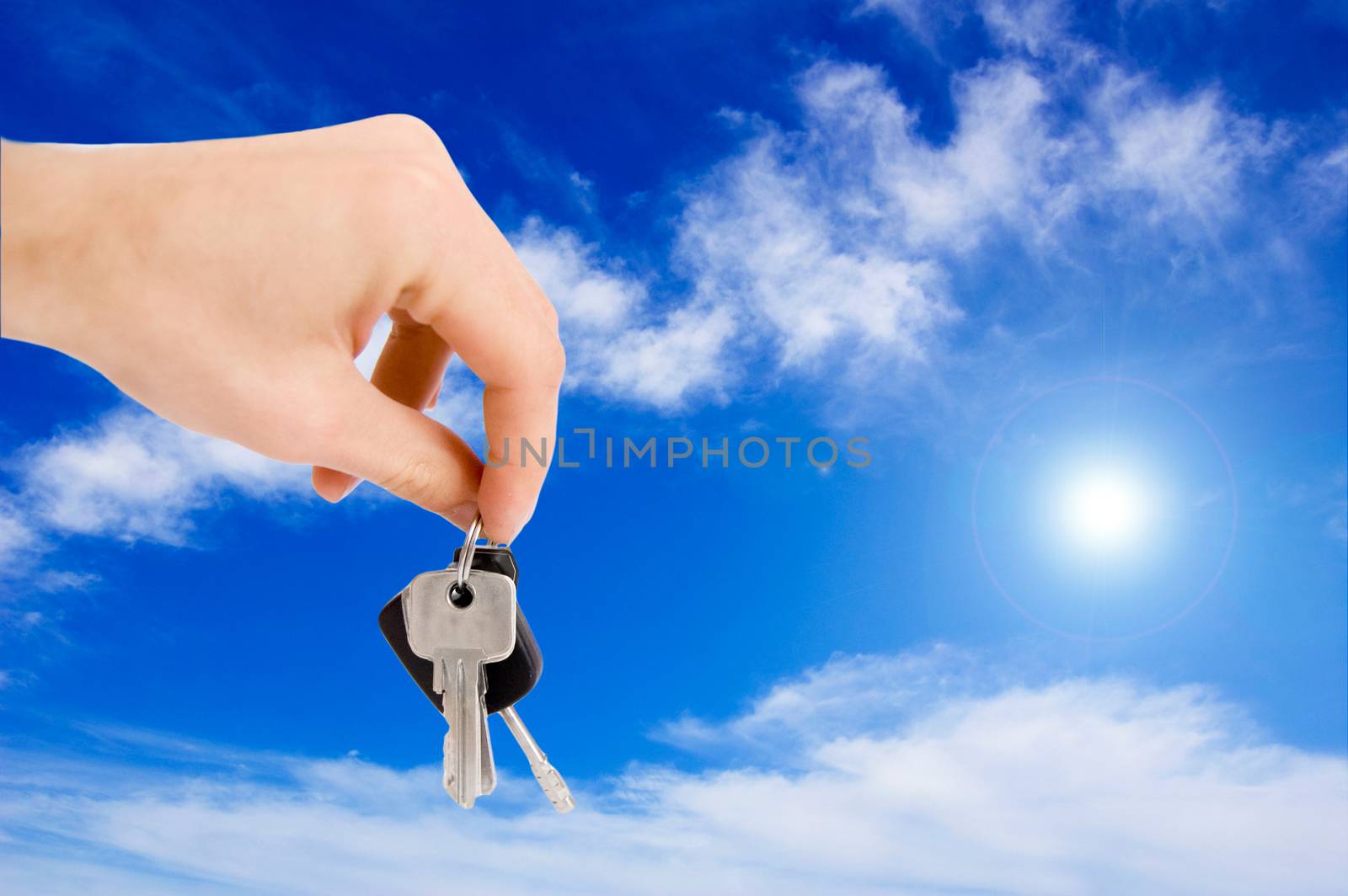 Hand holding keys against blue sky.