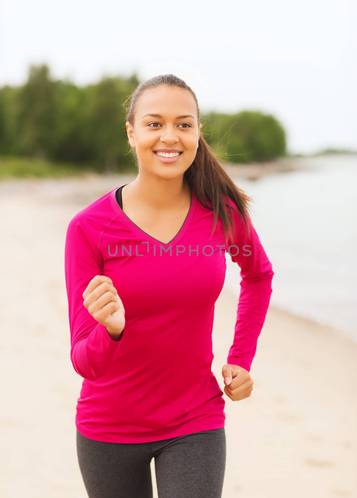 smiling woman running on track outdoors by dolgachov