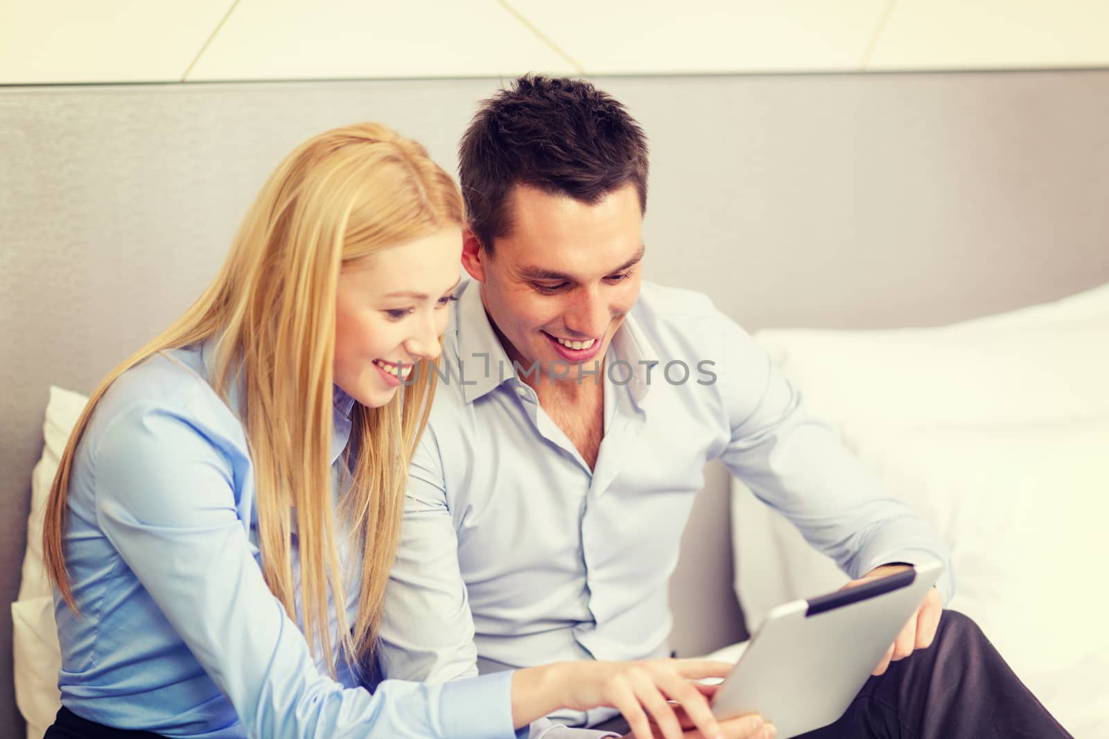 business, hotel, trave and technology concept - smiling couple with tablet pc computer in hotel room