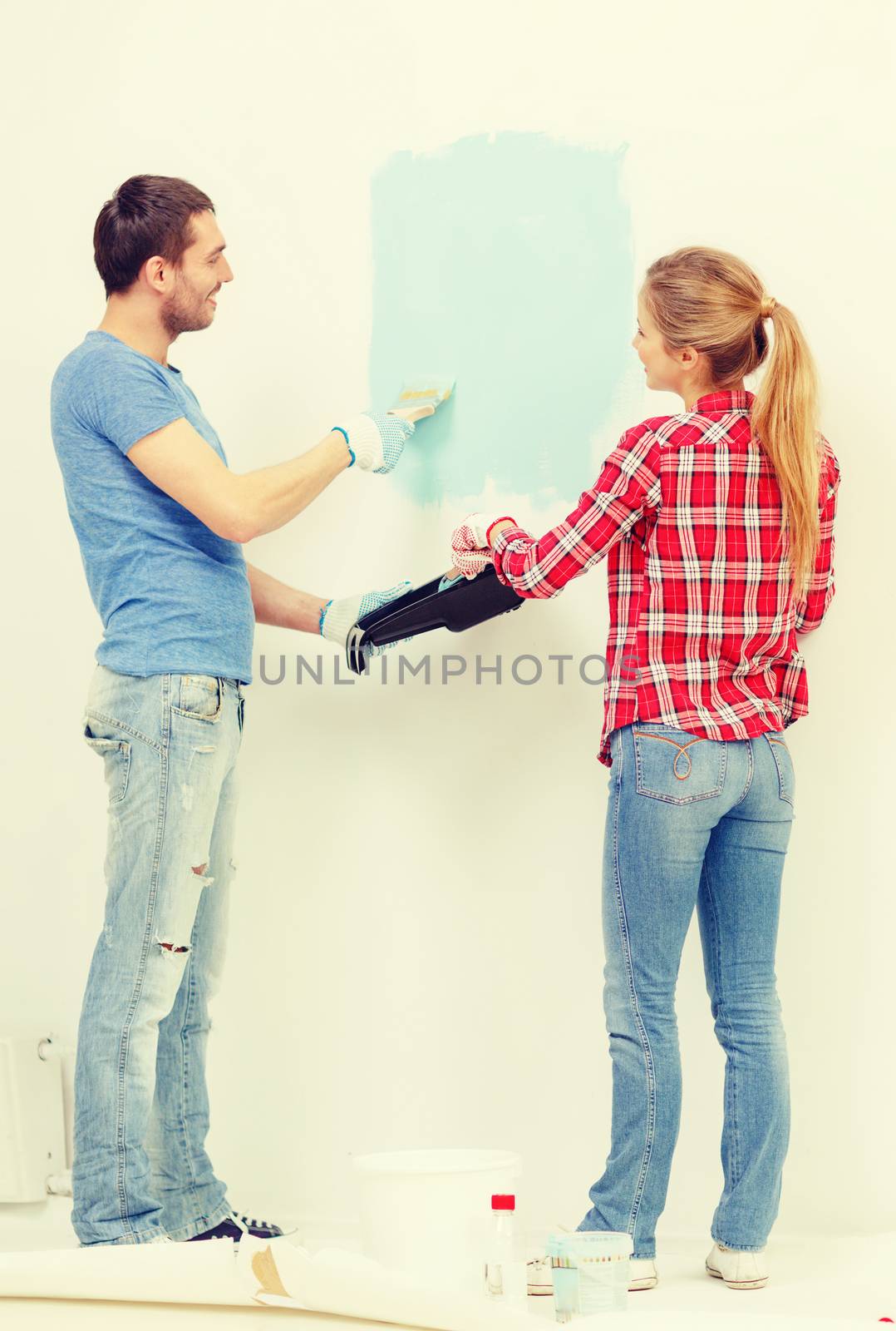 smiling couple painting wall at home by dolgachov