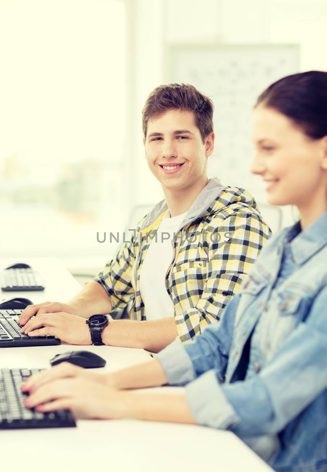 smiling boy with girl in computer class at school by dolgachov