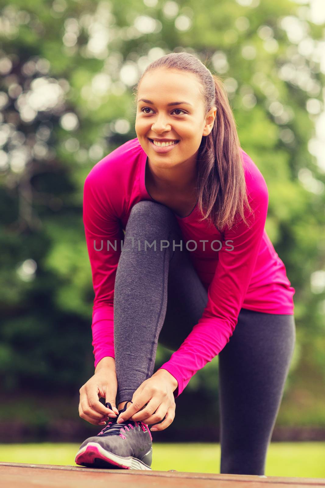 sport, exercise, park and lifestyle concept - smiling african american woman exercising outdoors