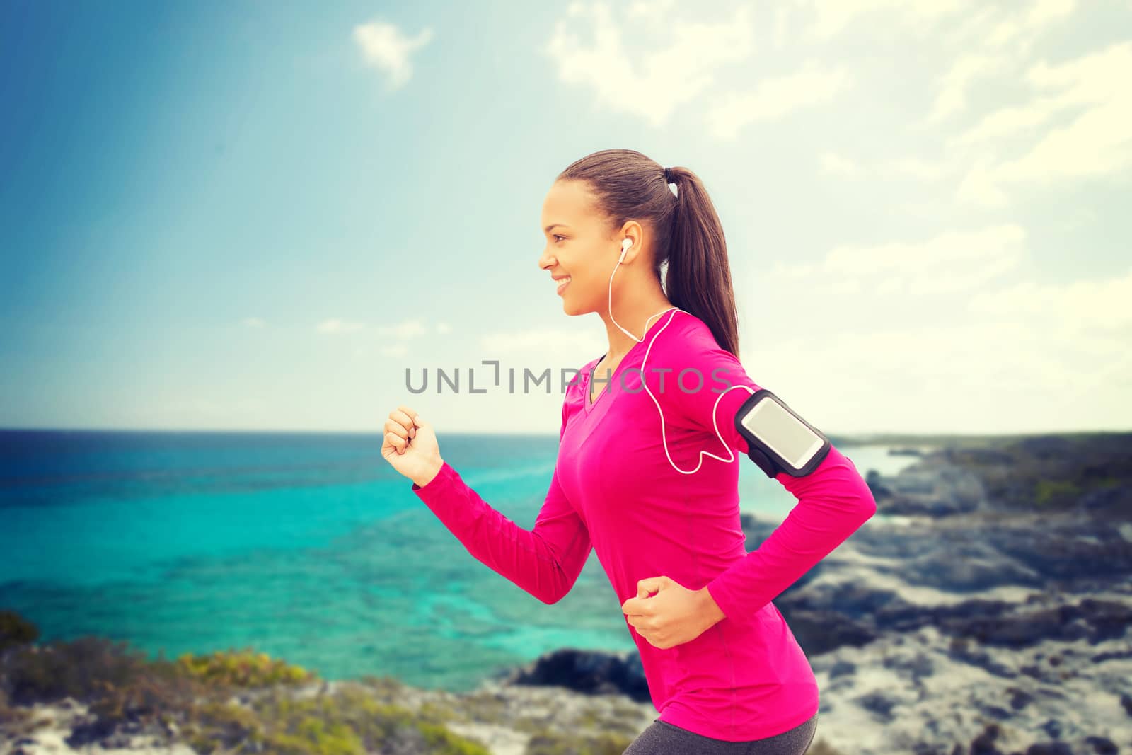 sport, fitness, health, technology and people concept - smiling young african american woman running with smartphone and earphones outdoors