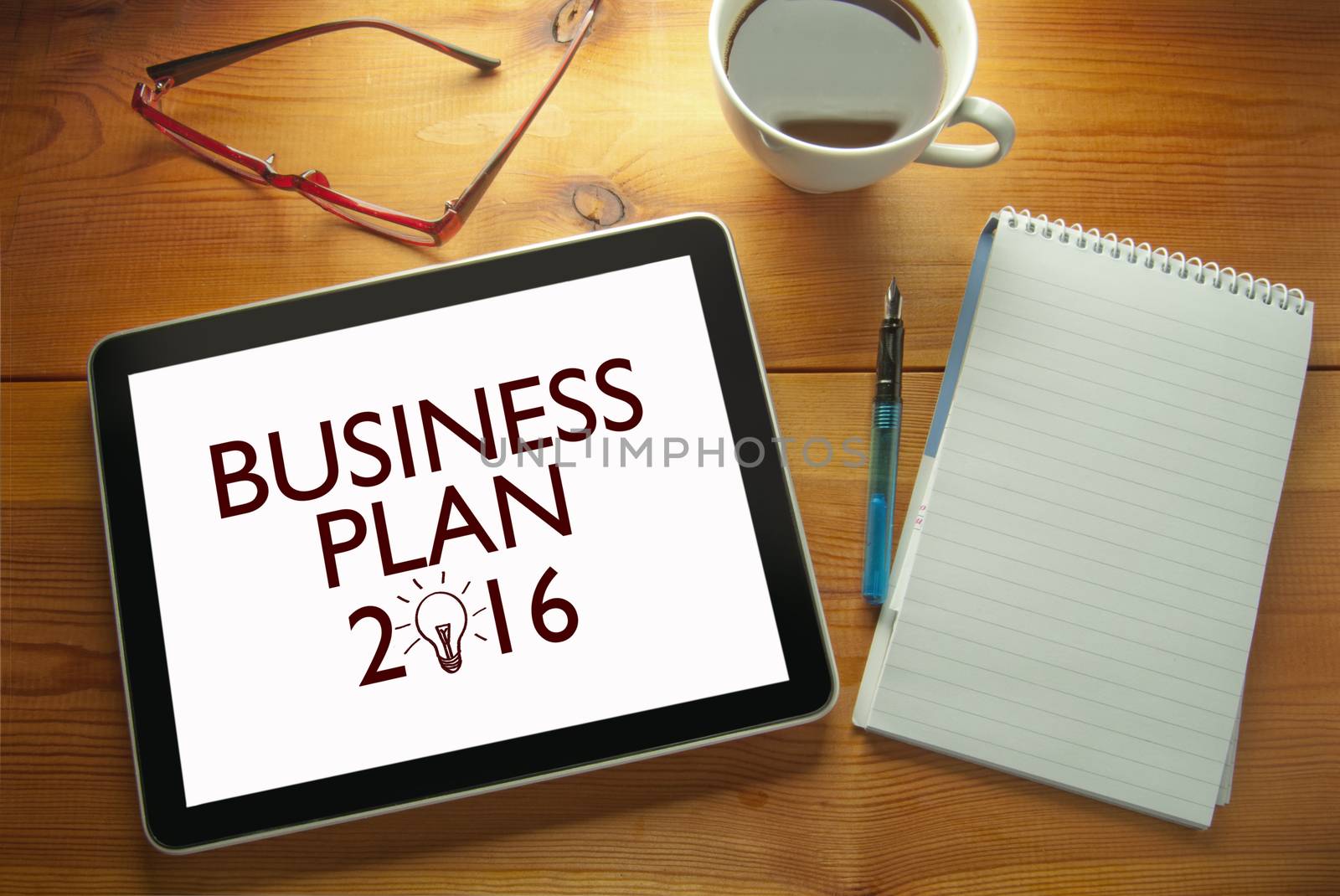 Work desk with computer tablet document entitled business plan 2016 