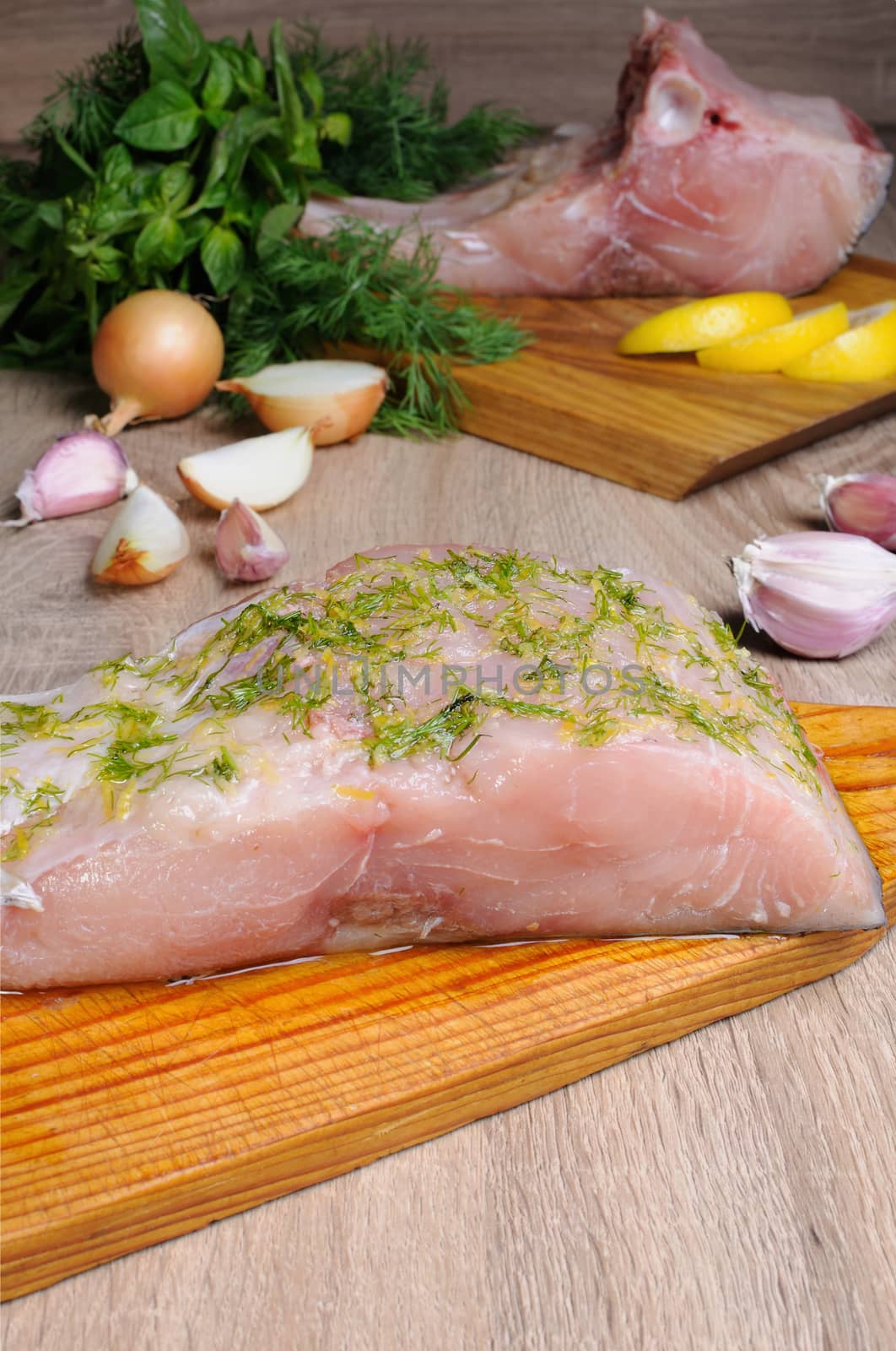 Raw piec carp on wooden board with fresh herbs and spices