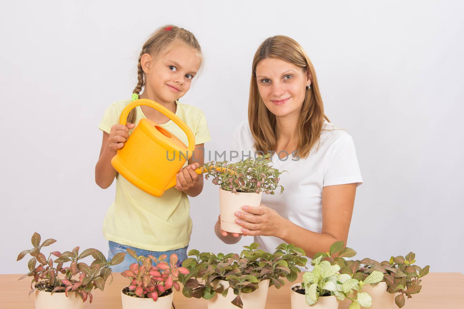 Mom and daughter watering houseplants by Madhourse