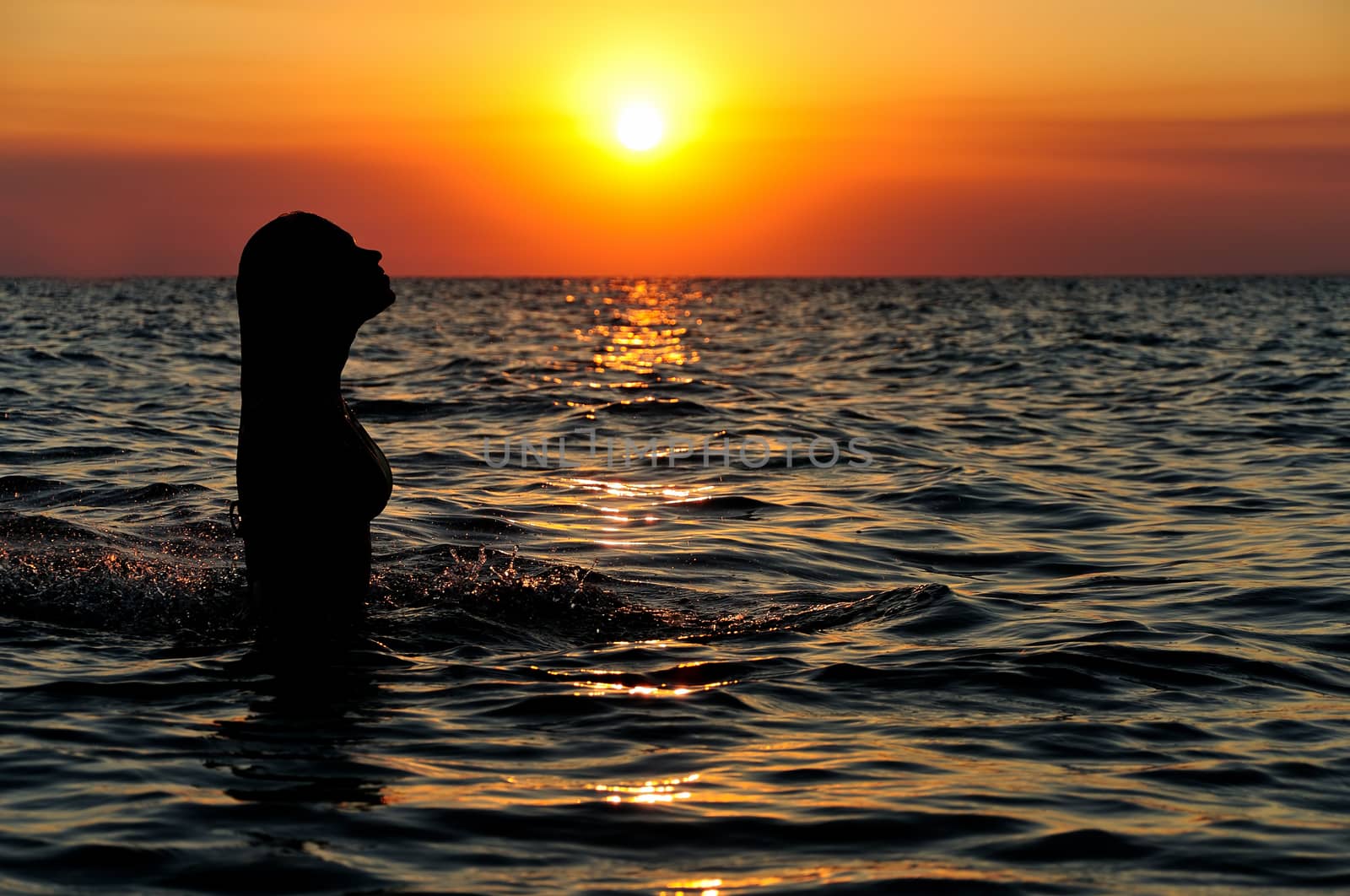 silhouette of a girl in ocean on sunset
