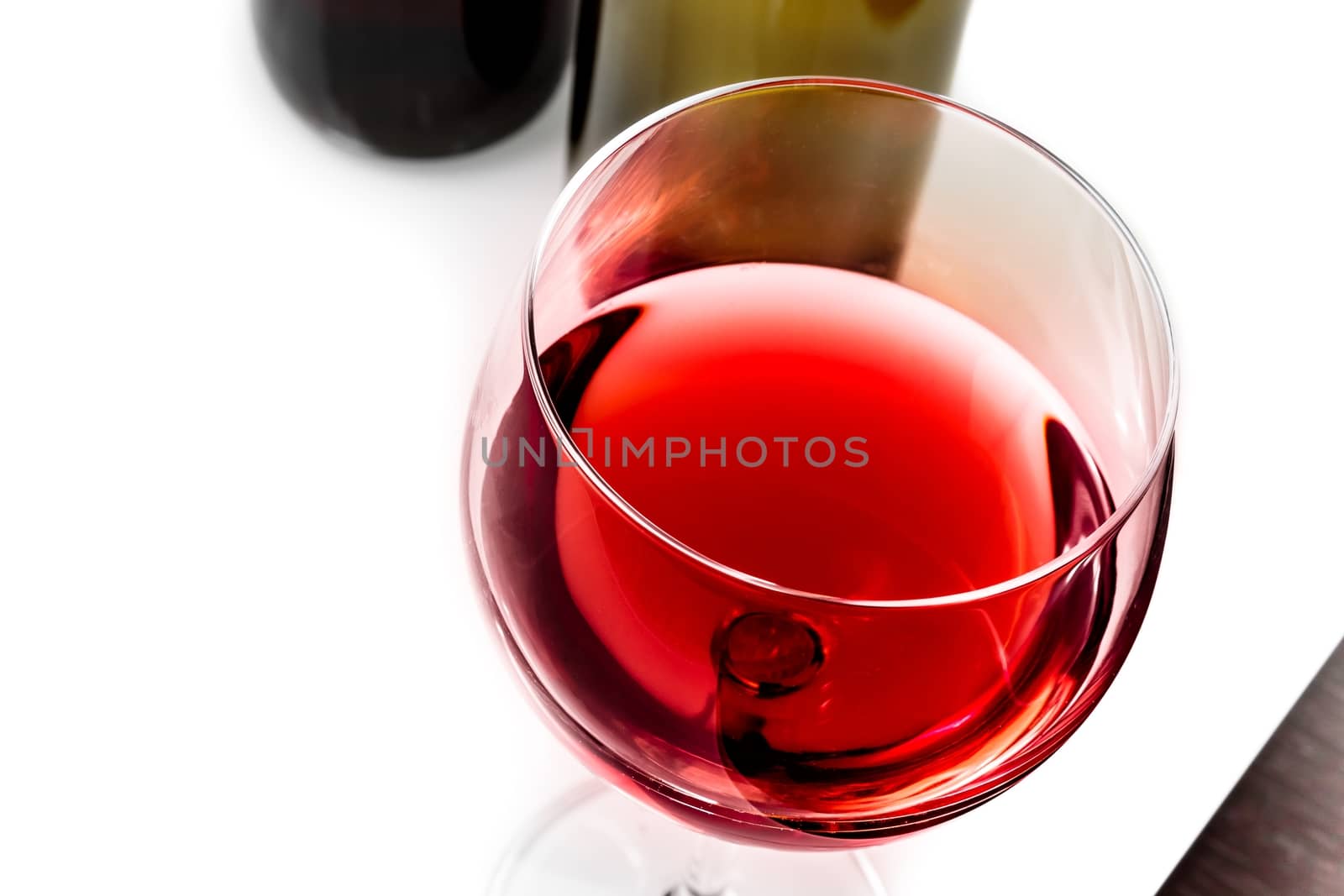 top of view of red wine glass near wine bottles by donfiore