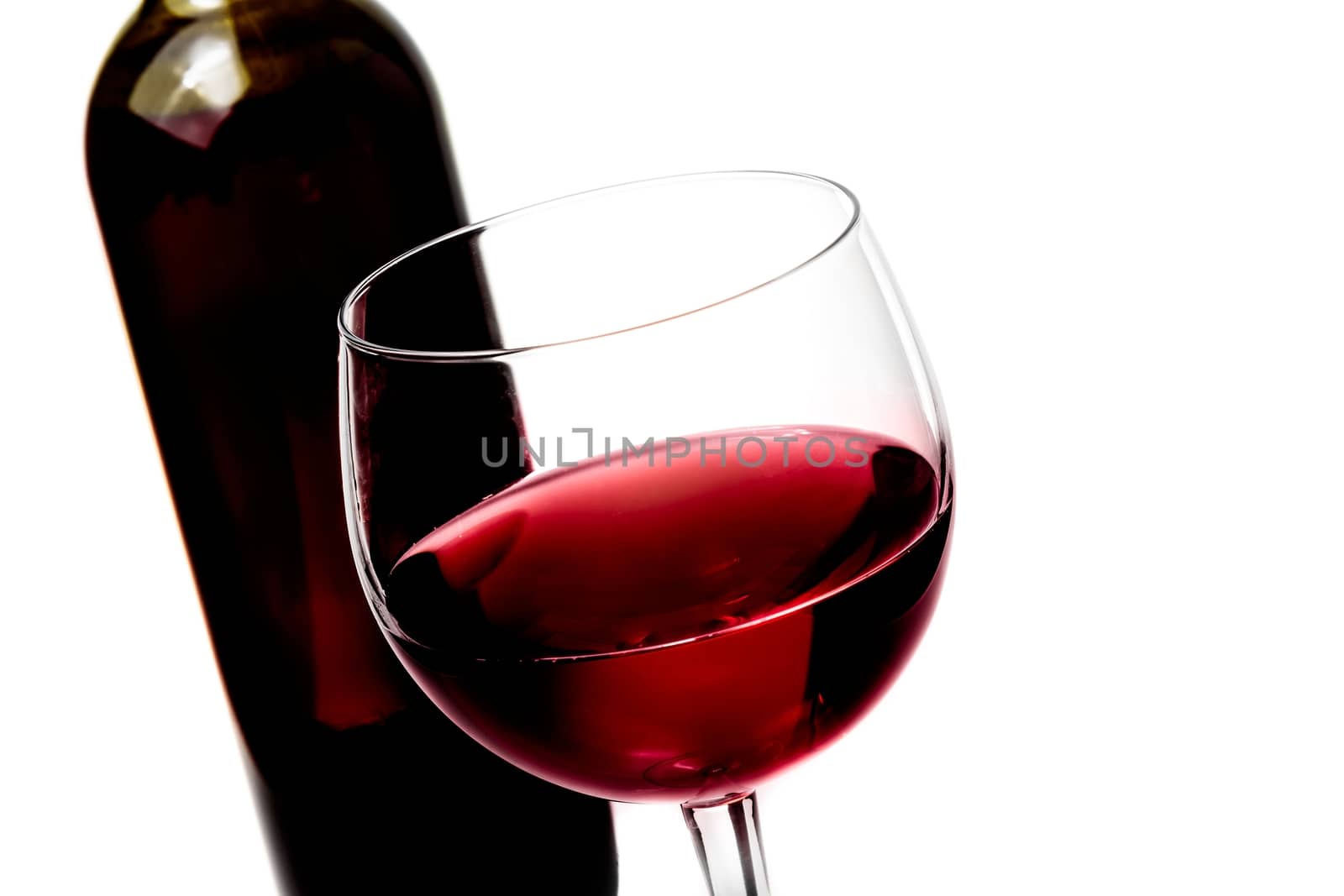 red wine glass near wine bottle on white background