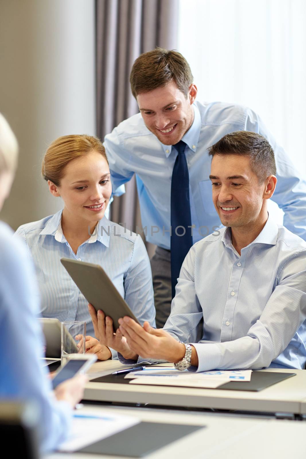 smiling business people with tablet pc in office by dolgachov