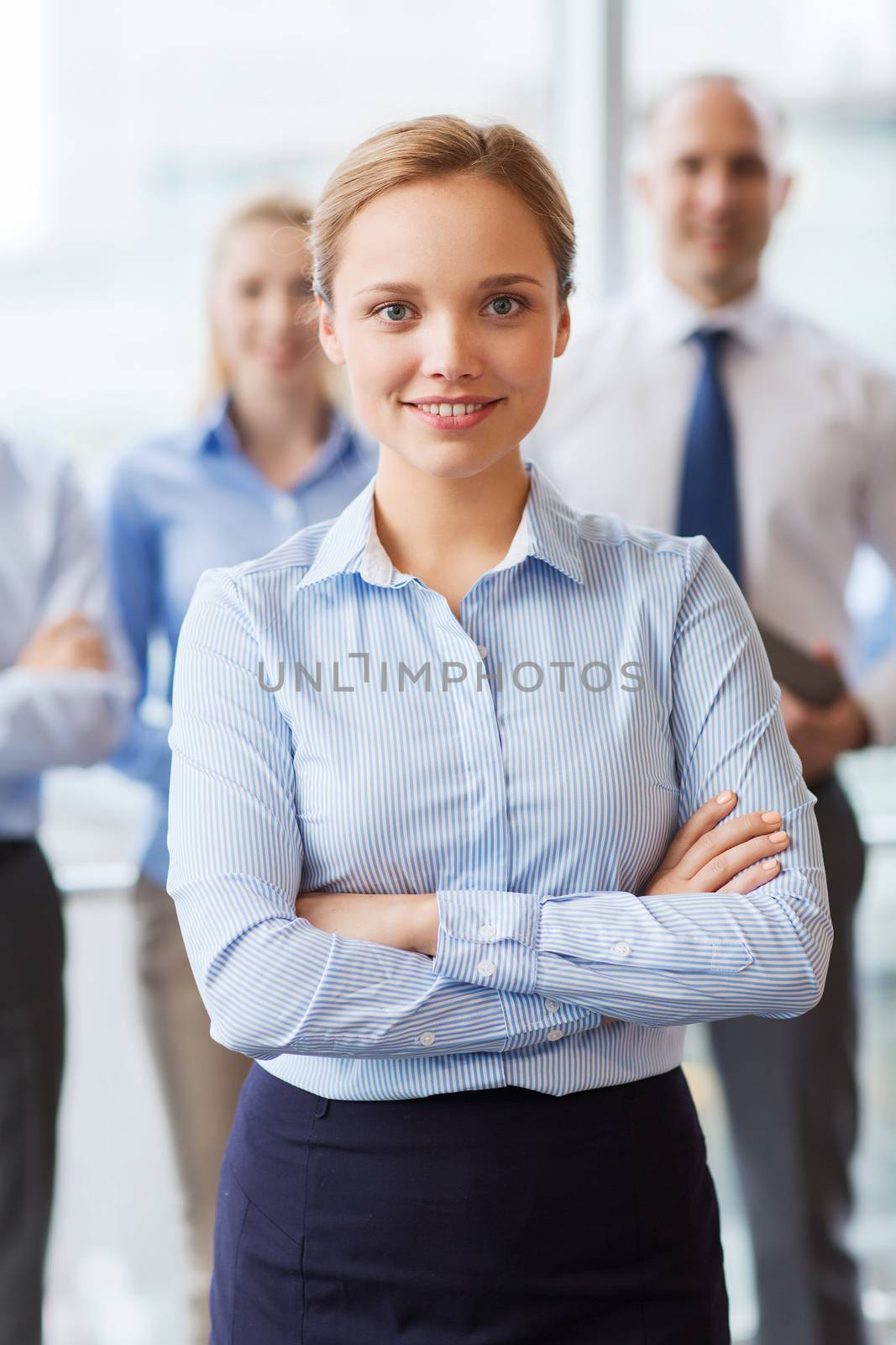 smiling businesswoman with colleagues in office by dolgachov