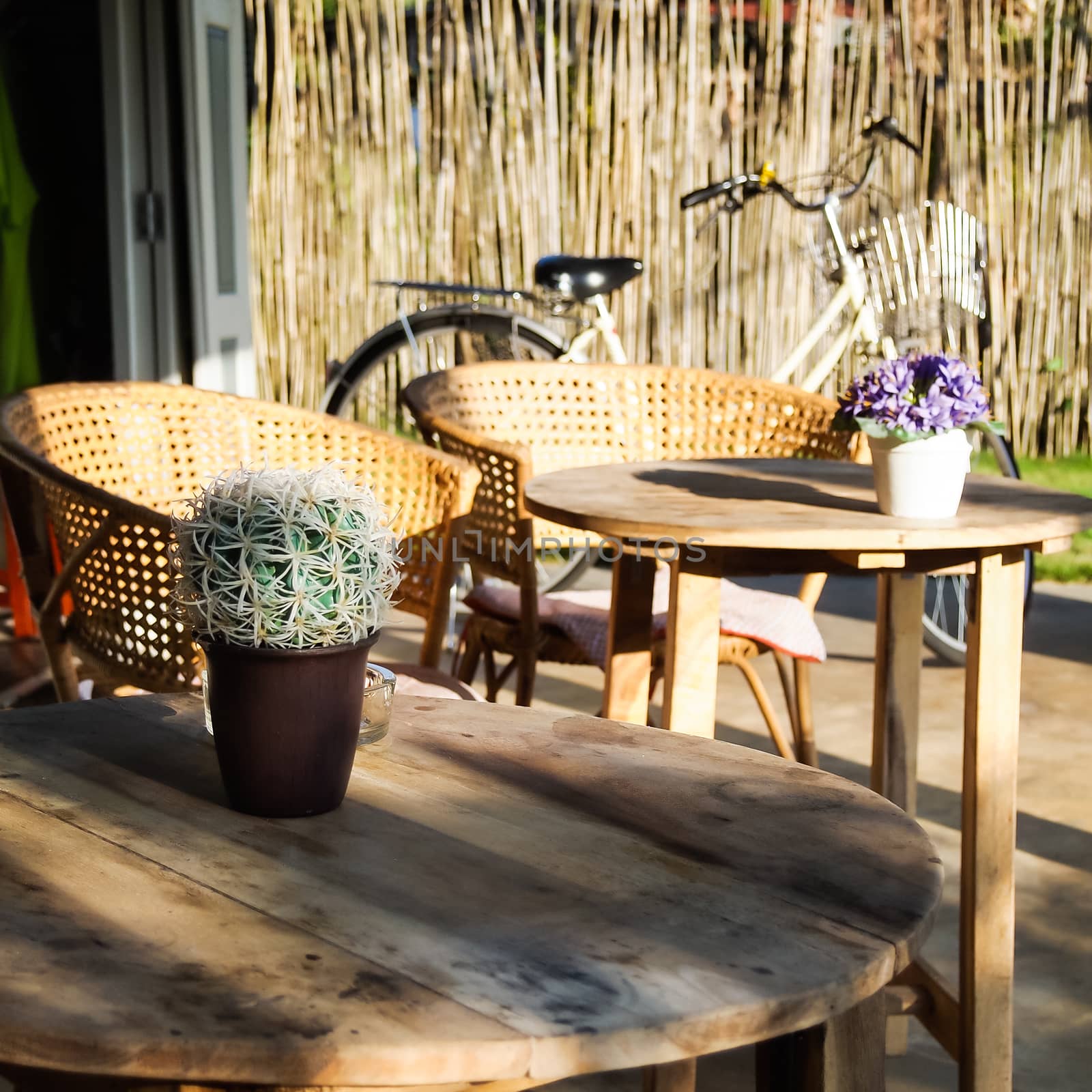 Wooden table seats peace , chairs , flower vase, bicycle and cactus in coffee cafe