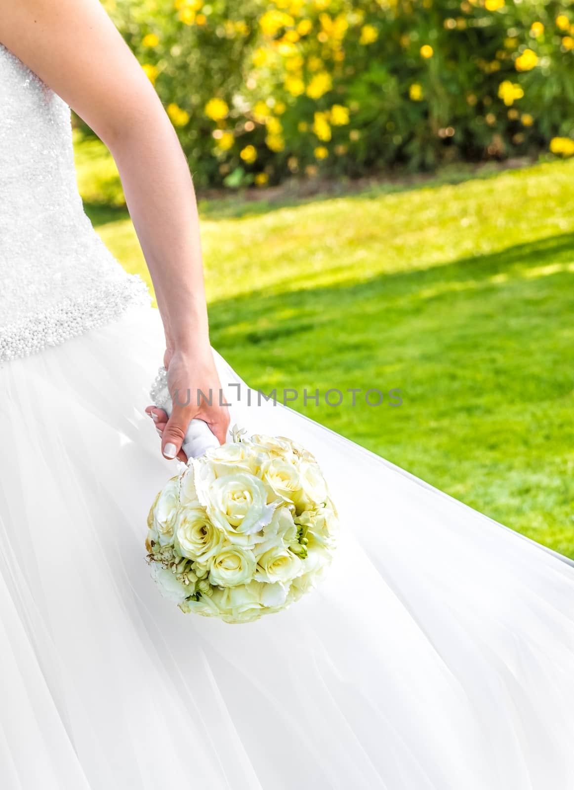 bride holds in hand a wedding bouquet of flowers in a garden by donfiore