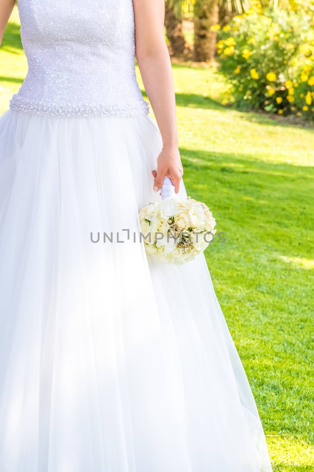 bride holds in hand a wedding bouquet of flowers in a garden by donfiore