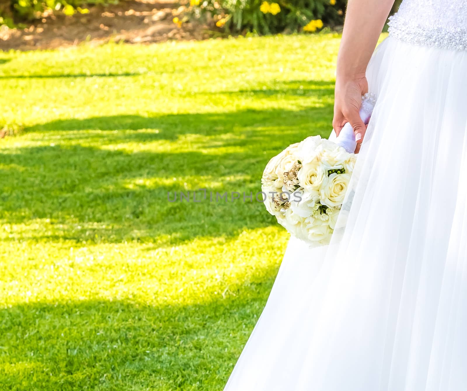detail of wedding bouquet of flowers in hand of a bride in a green garden with space for text