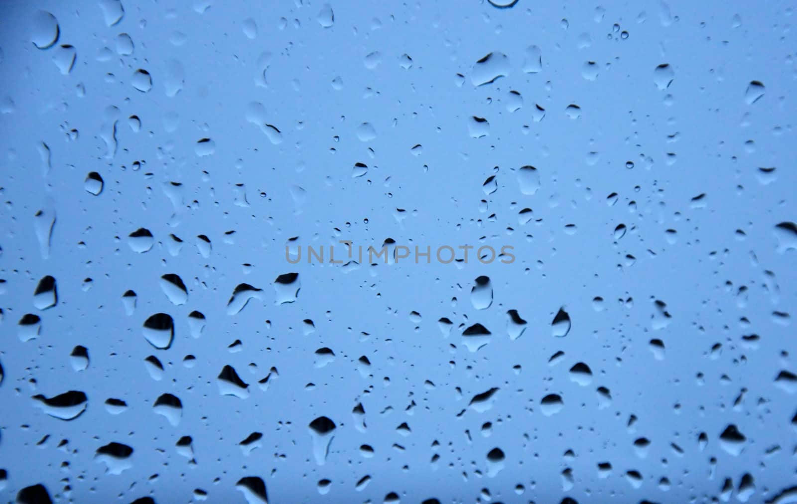 raindrops on window in front of blue backgrond