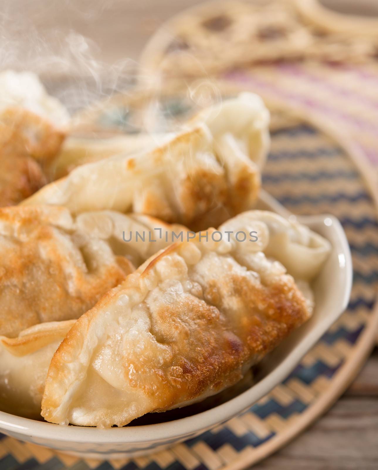 Fresh pan fried dumplings on bowl with hot steams. Asian food on rustic vintage wooden background.
