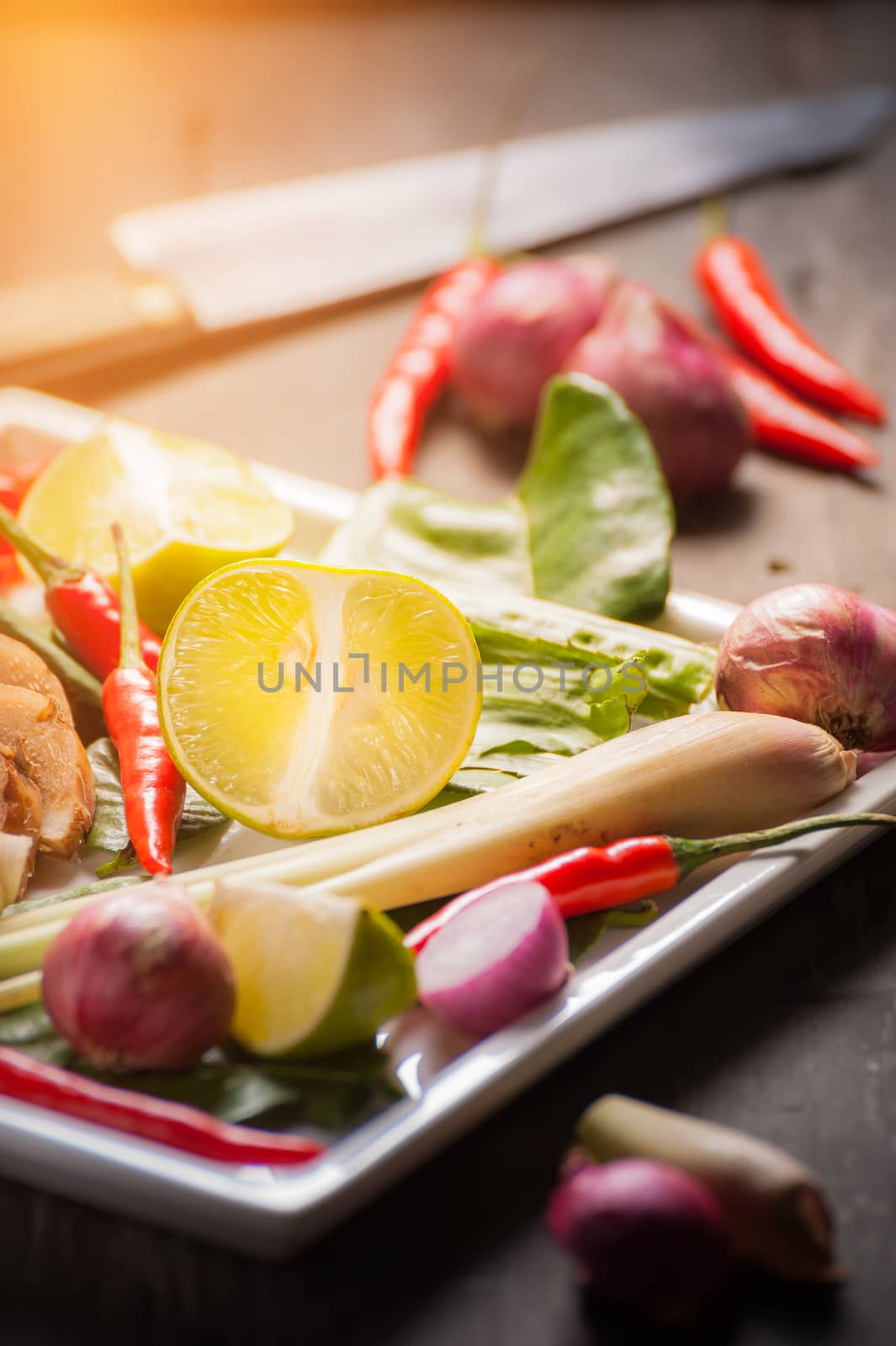 Ingredients set for Thai spicy soup (Tom-yum) include lemon, galangal, red chili, red onion, lemongrass, and kaffir lime leaf on wood table with low key scene