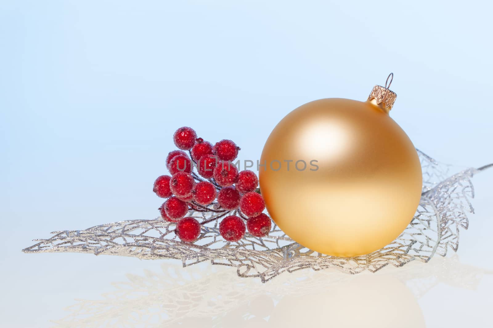 New Year background with golden glass toy  and branch of rowan on silver decorative leaf