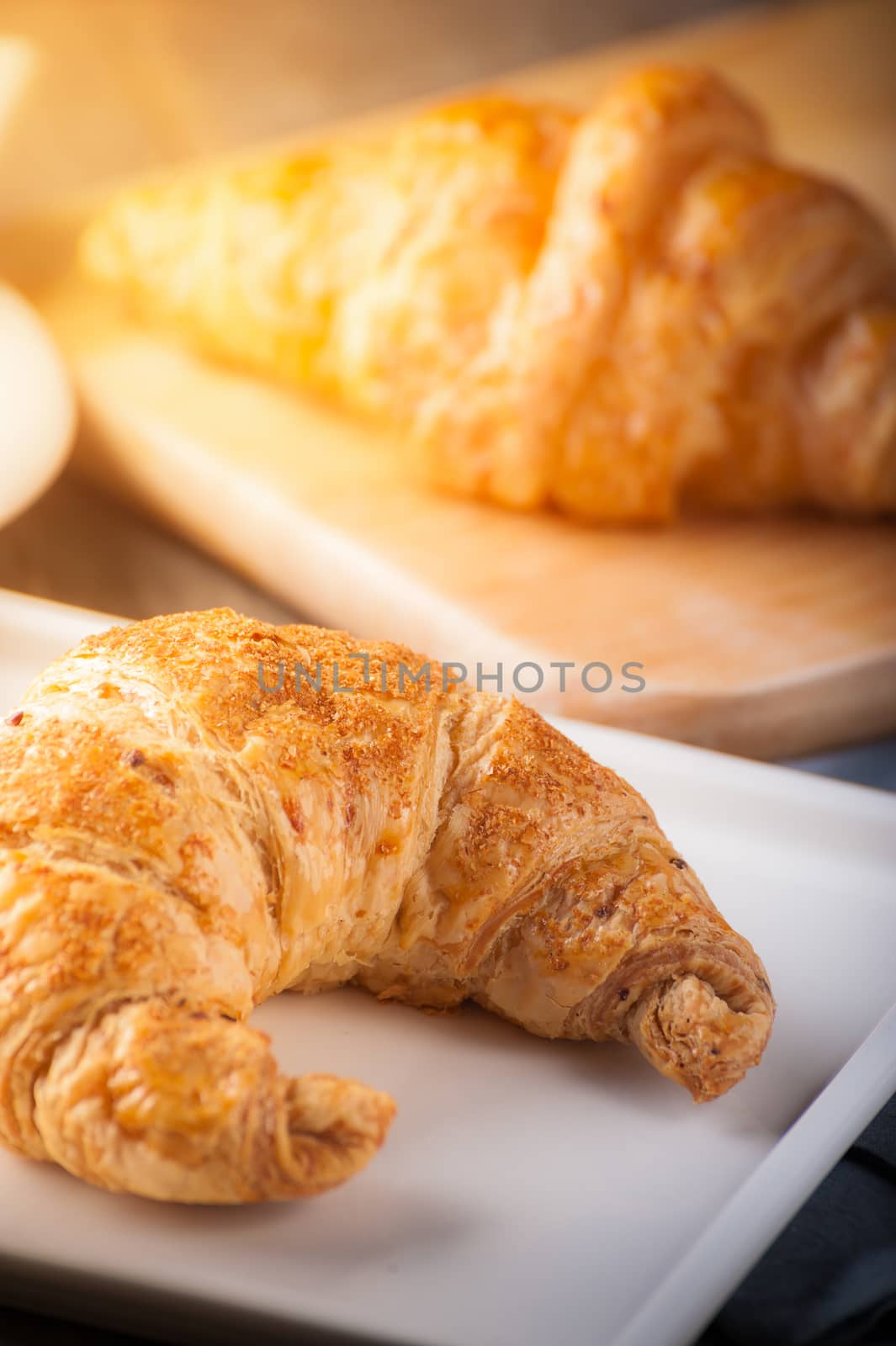 Whole wheat croissant on ceramic dish with morning scene