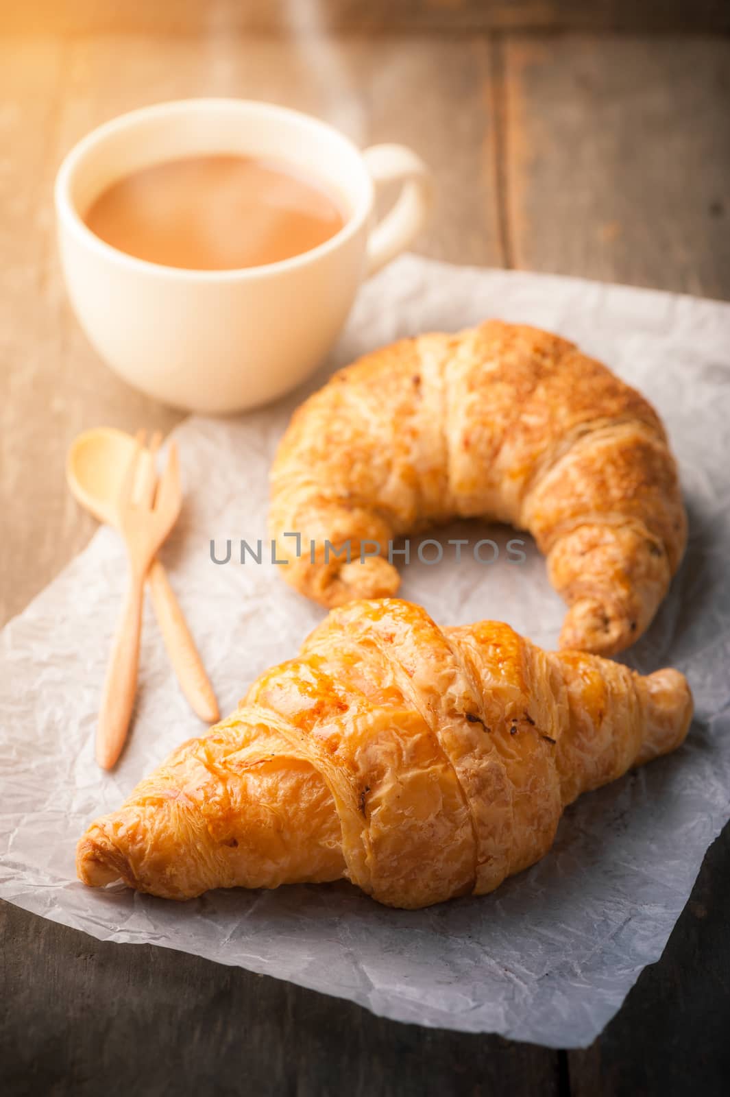 Butter croissant, whole wheat croissant, and a cup of hot chocolate on wood table with morning scene