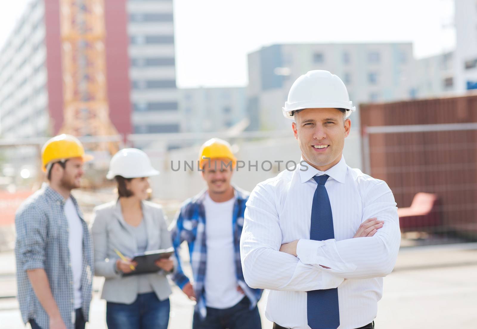 group of smiling builders in hardhats outdoors by dolgachov