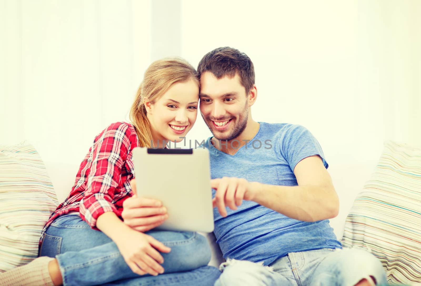 smiling couple with tablet pc computer at home by dolgachov
