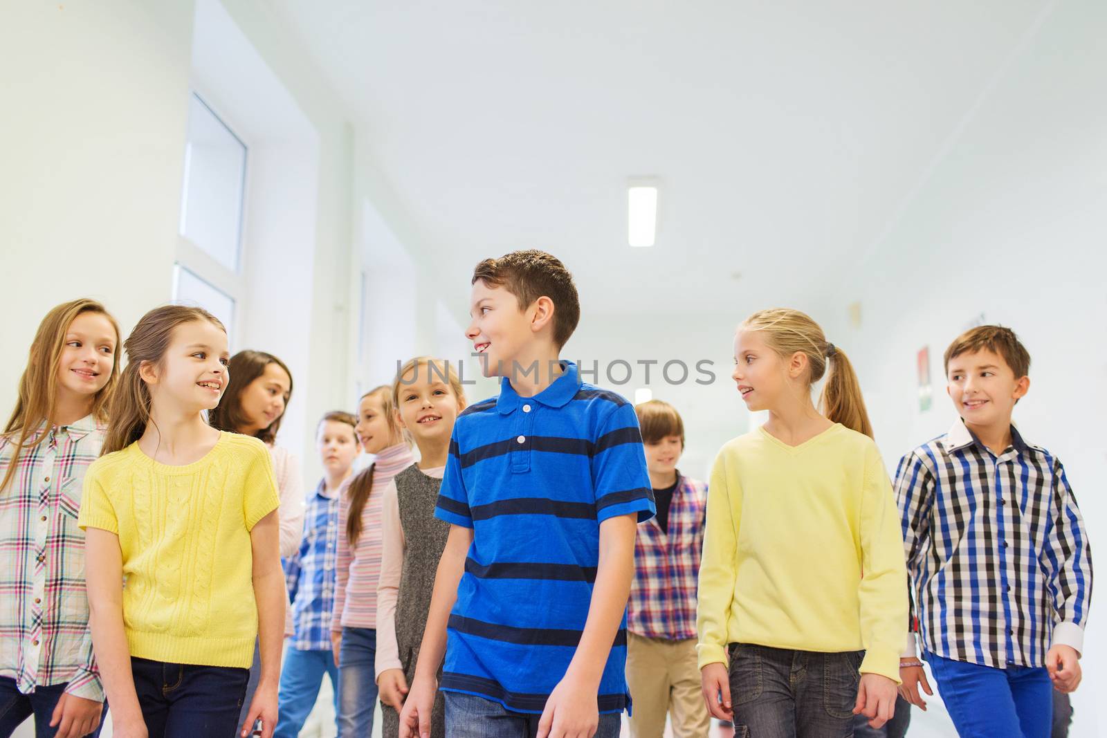 education, elementary school, drinks, children and people concept - group of smiling school kids walking in corridor