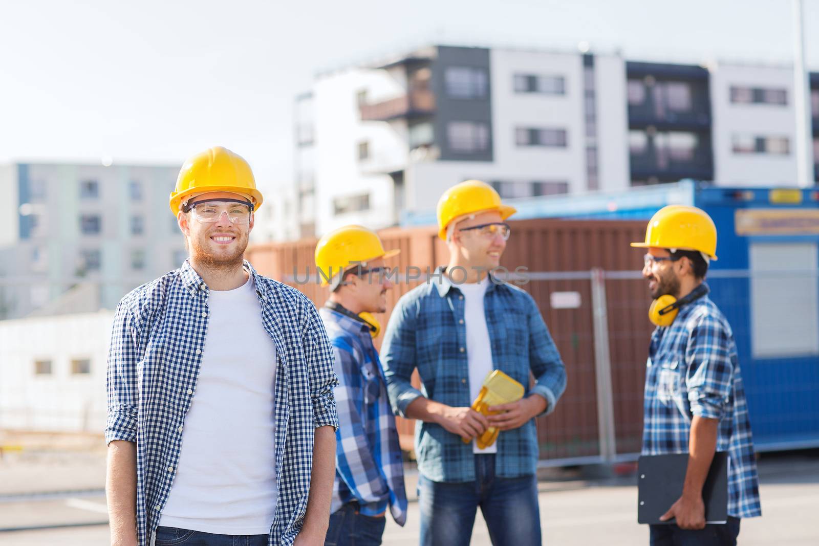 group of smiling builders in hardhats outdoors by dolgachov